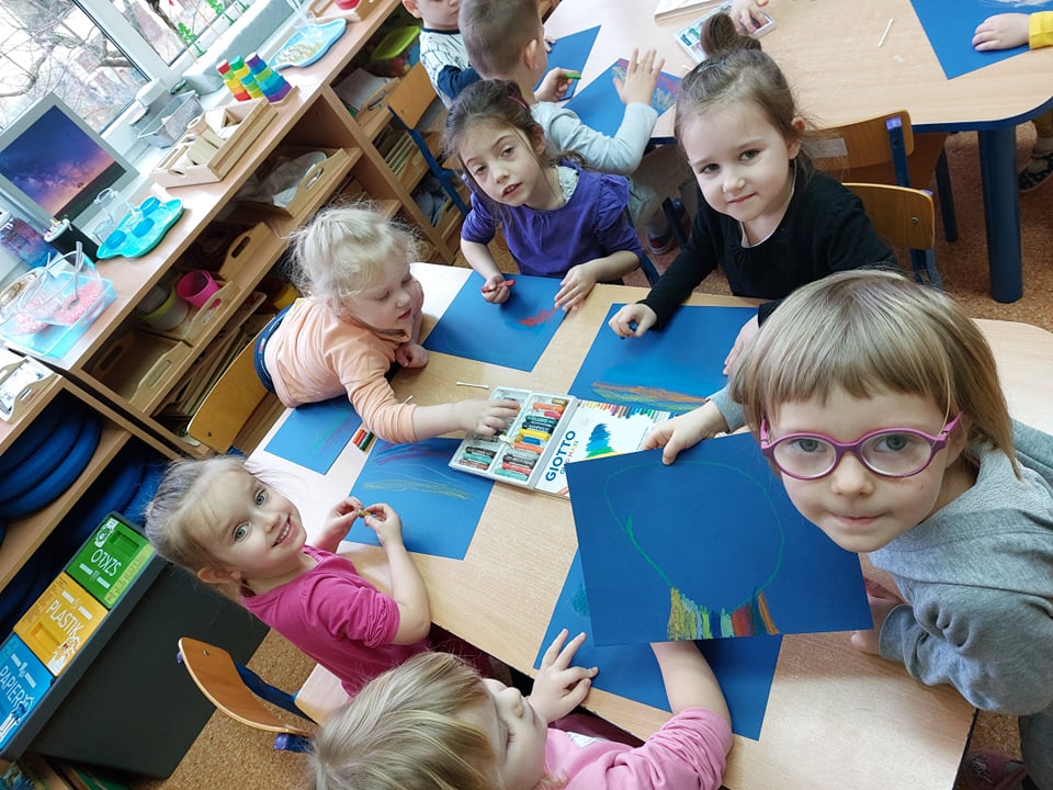 Dzieci wykonują pracę plastyczną na niebieskich kartkach