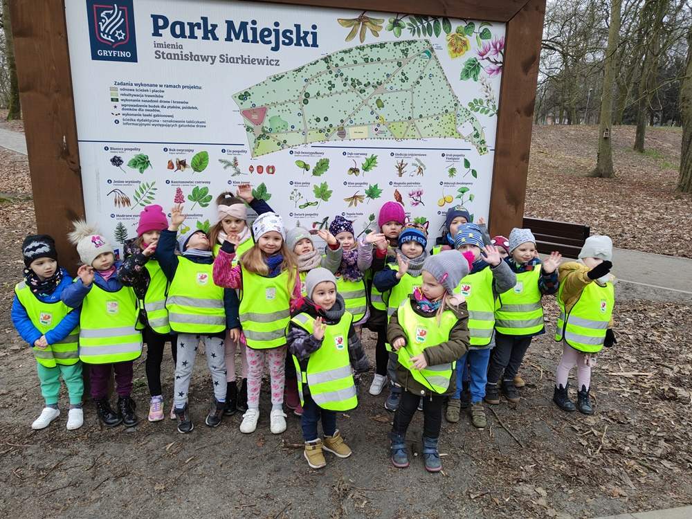 Dzieci stoją obok tablicy z mapą, na której umieszczona jest informacja o gatunkach drzew