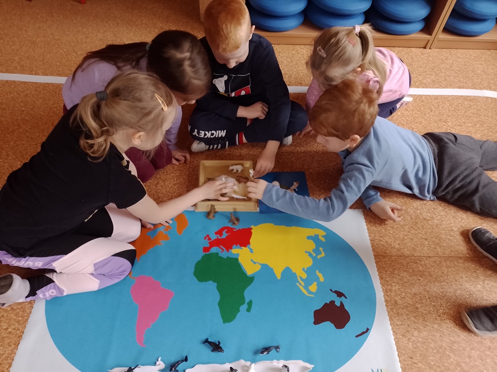Dzieci poprzez zabawę na mapie globusa utrwalają wiedzę.