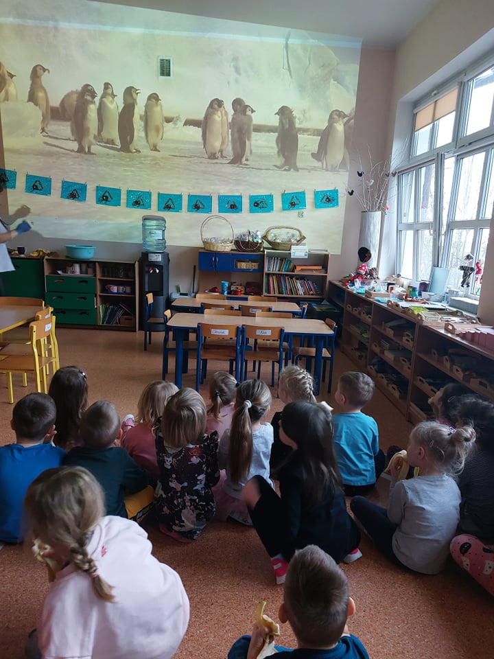 Dzieci oglądają prezentację multimedialną o kontynentach i zwierzętach na nich zamieszkujących.