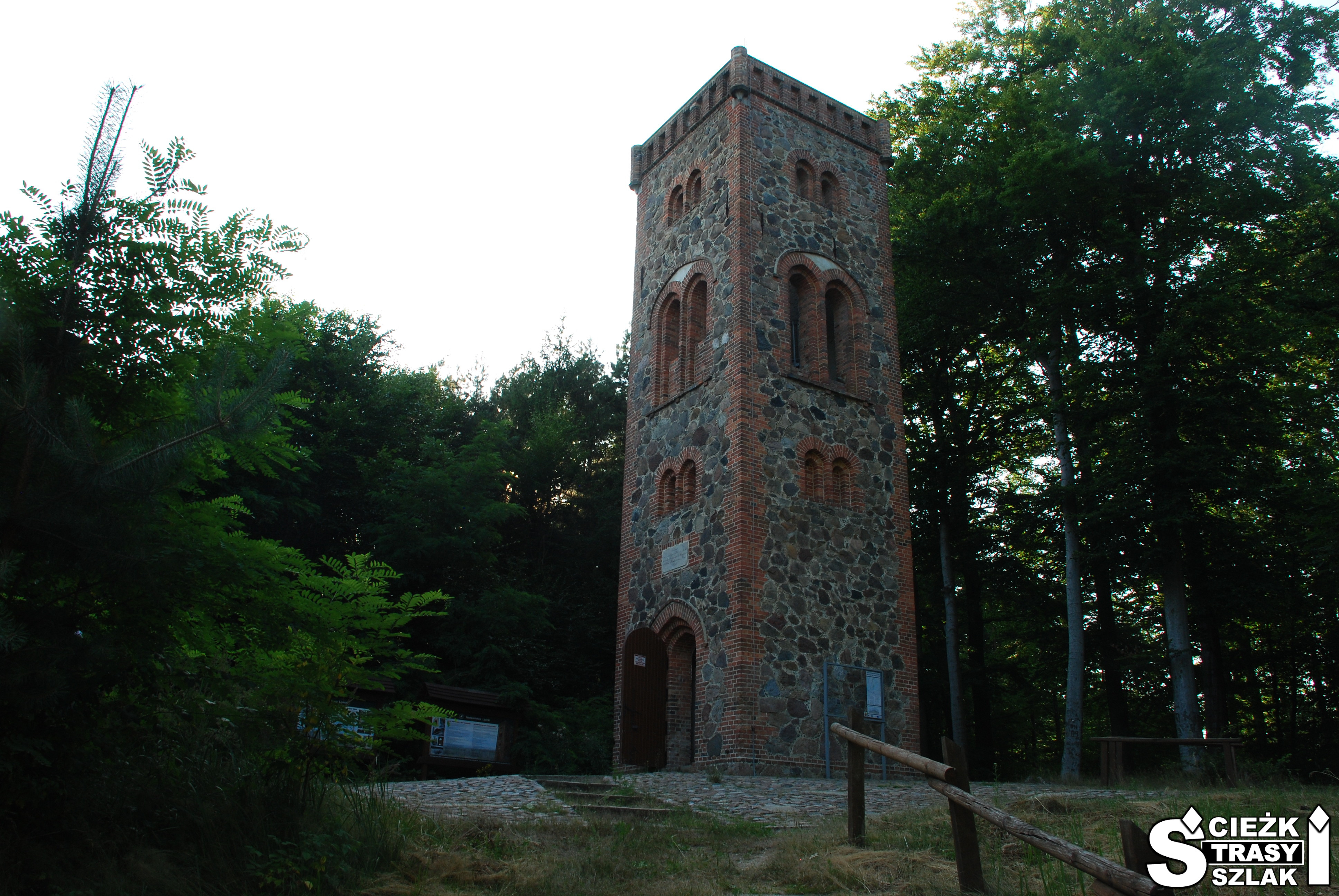 Wysoka, kwadratowa wieża widokowa z kamienia z tarasem widokowym na Zielony Las w Żarach