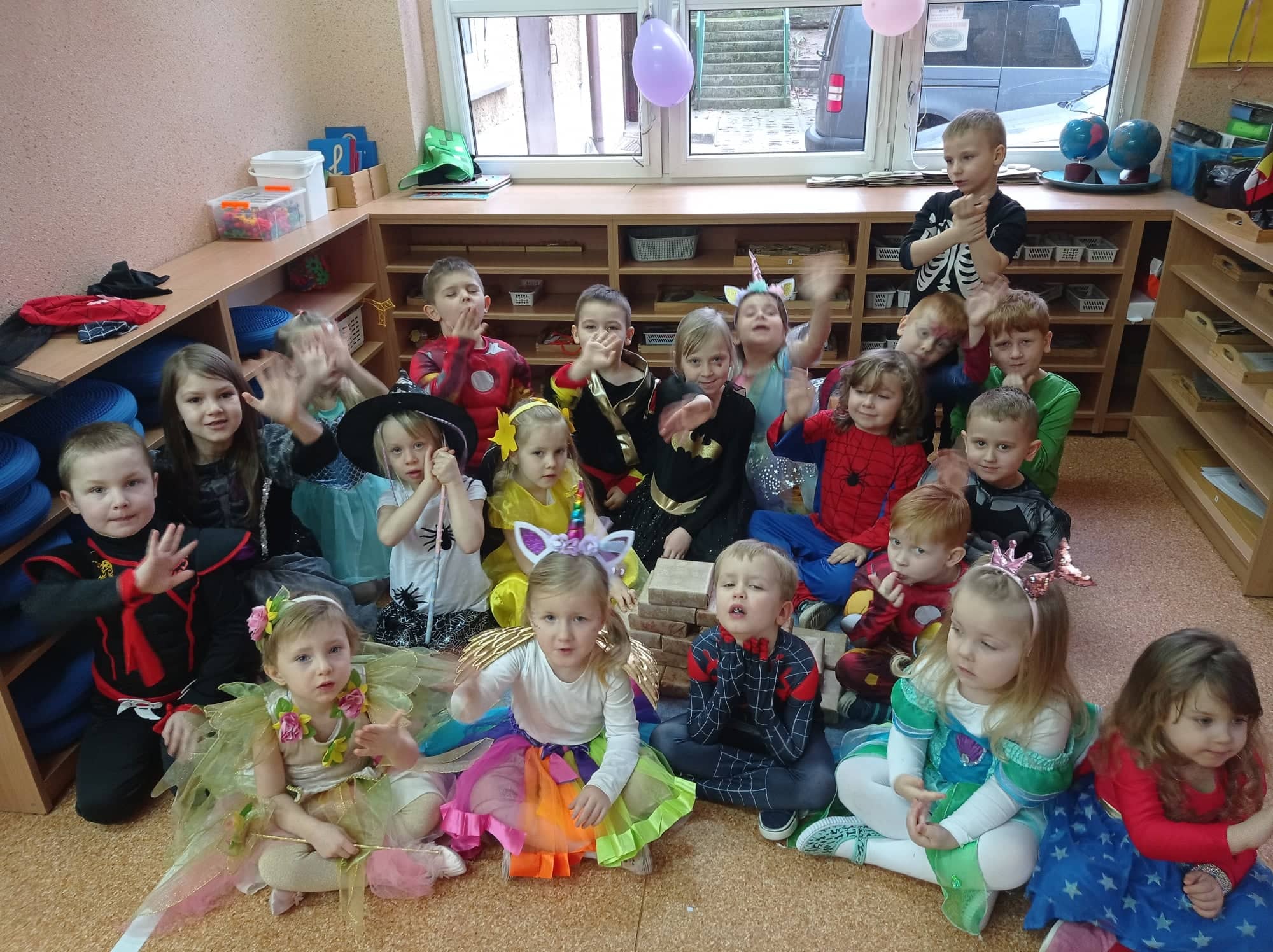 Wspólne zdjęcie dzieci w kolorowych strojach z prezentami w tle
