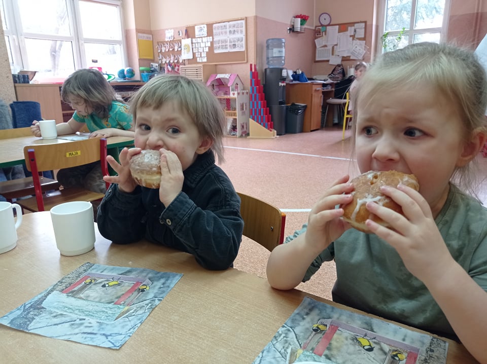 Wspólnie świętujemy Tłusty Czwartek. Dzieci jedzą pyszne pączki z dżemem.