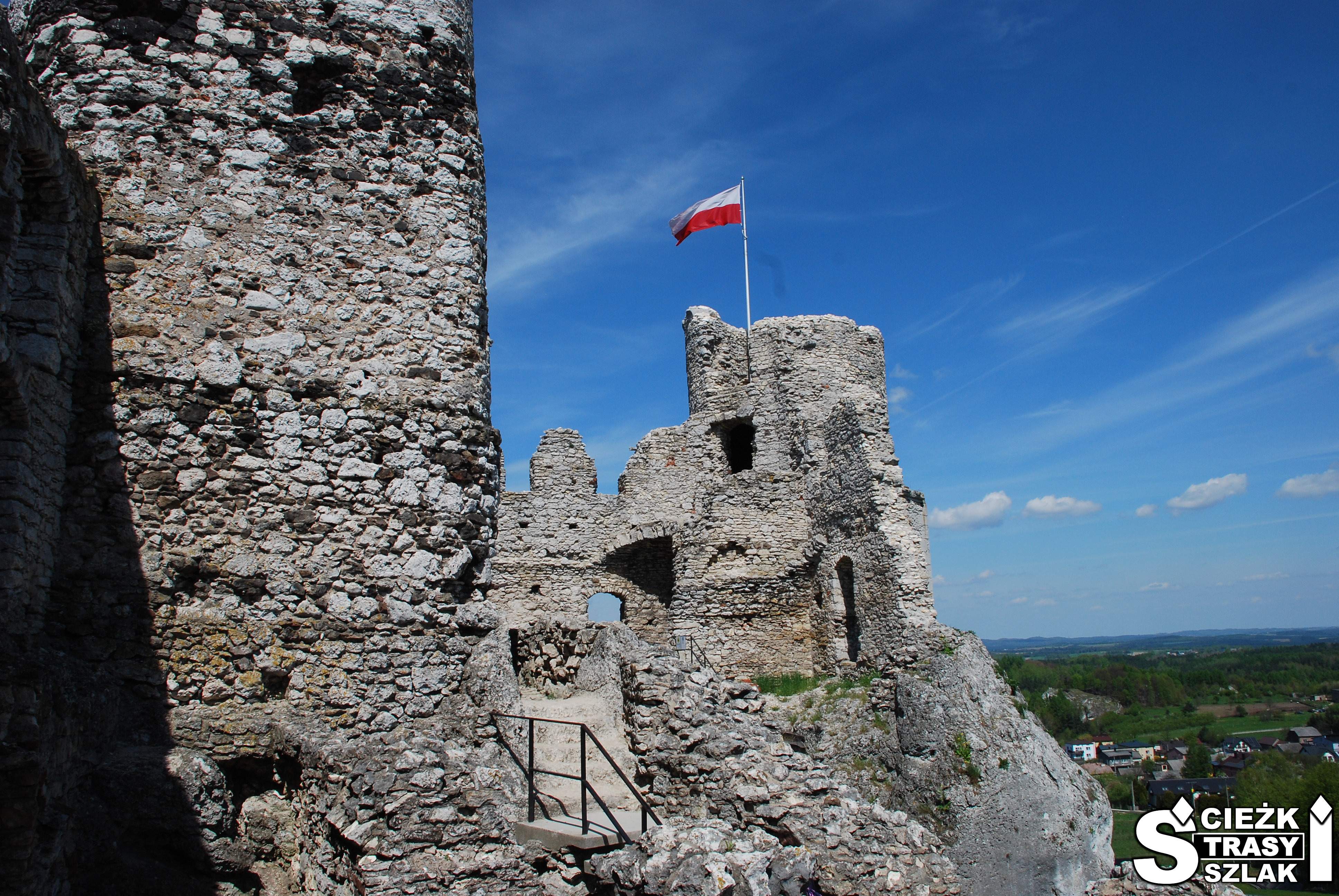Flaga Polski na szczycie cylindrycznej wieży wkomponowanej w kamienne ściany Zamku Ogrodzieniec w Podzamczu