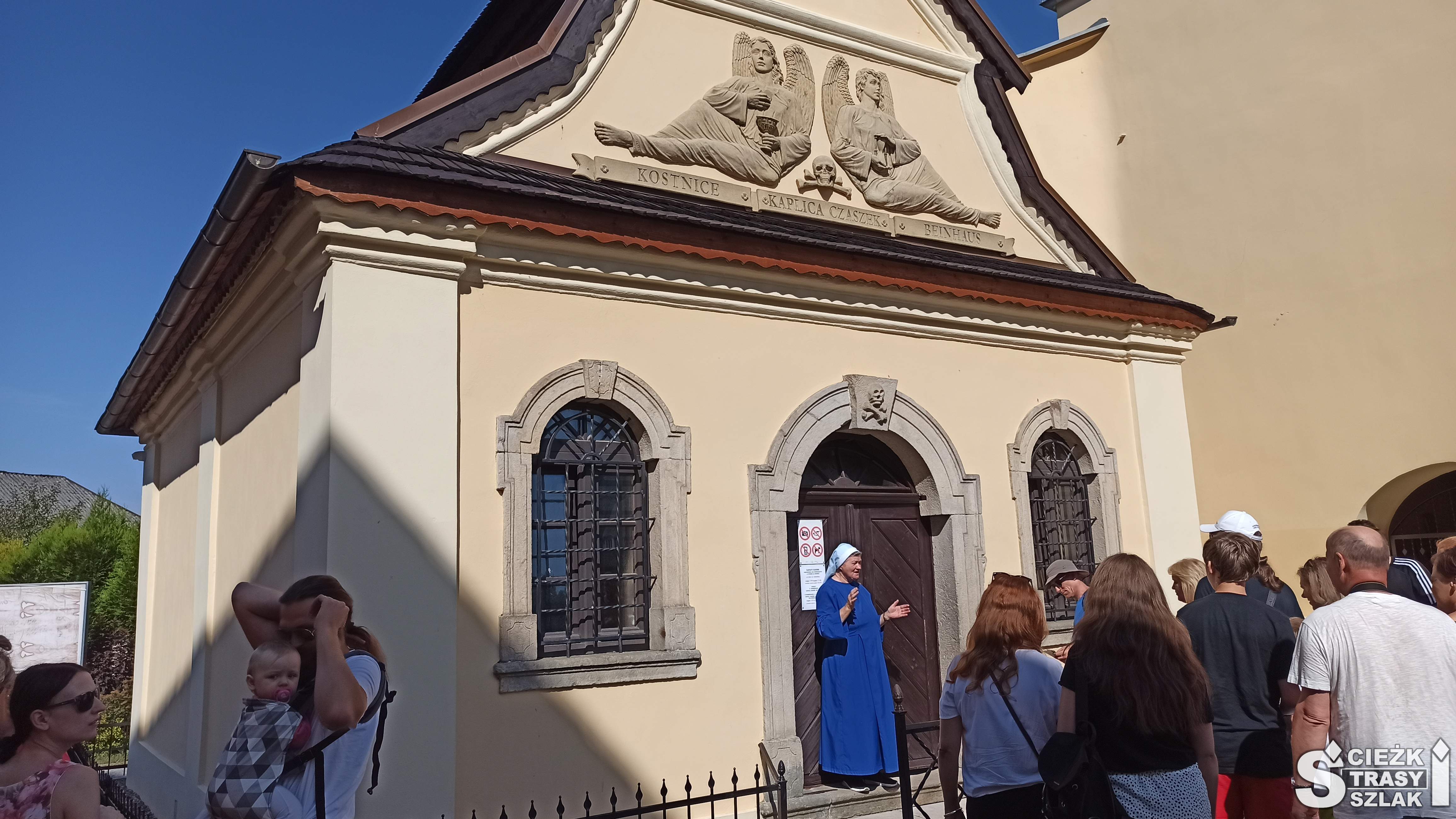 Turyści stojący przy wejściu do kaplicy czaszek, do środka której wprowadza zakonnica