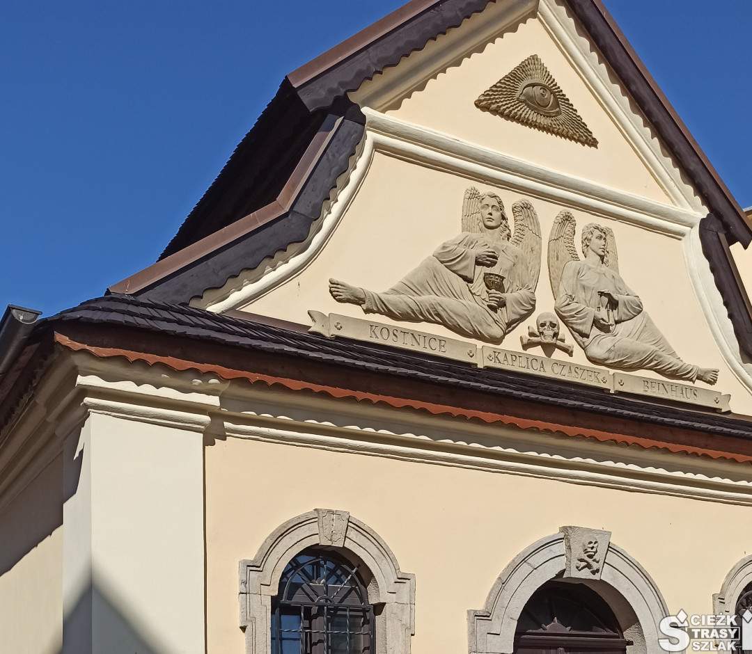 Murowana kaplica z wejściem usytuowanym pomiędzy dwoma oknami i pod płaskorzeźbami aniołów