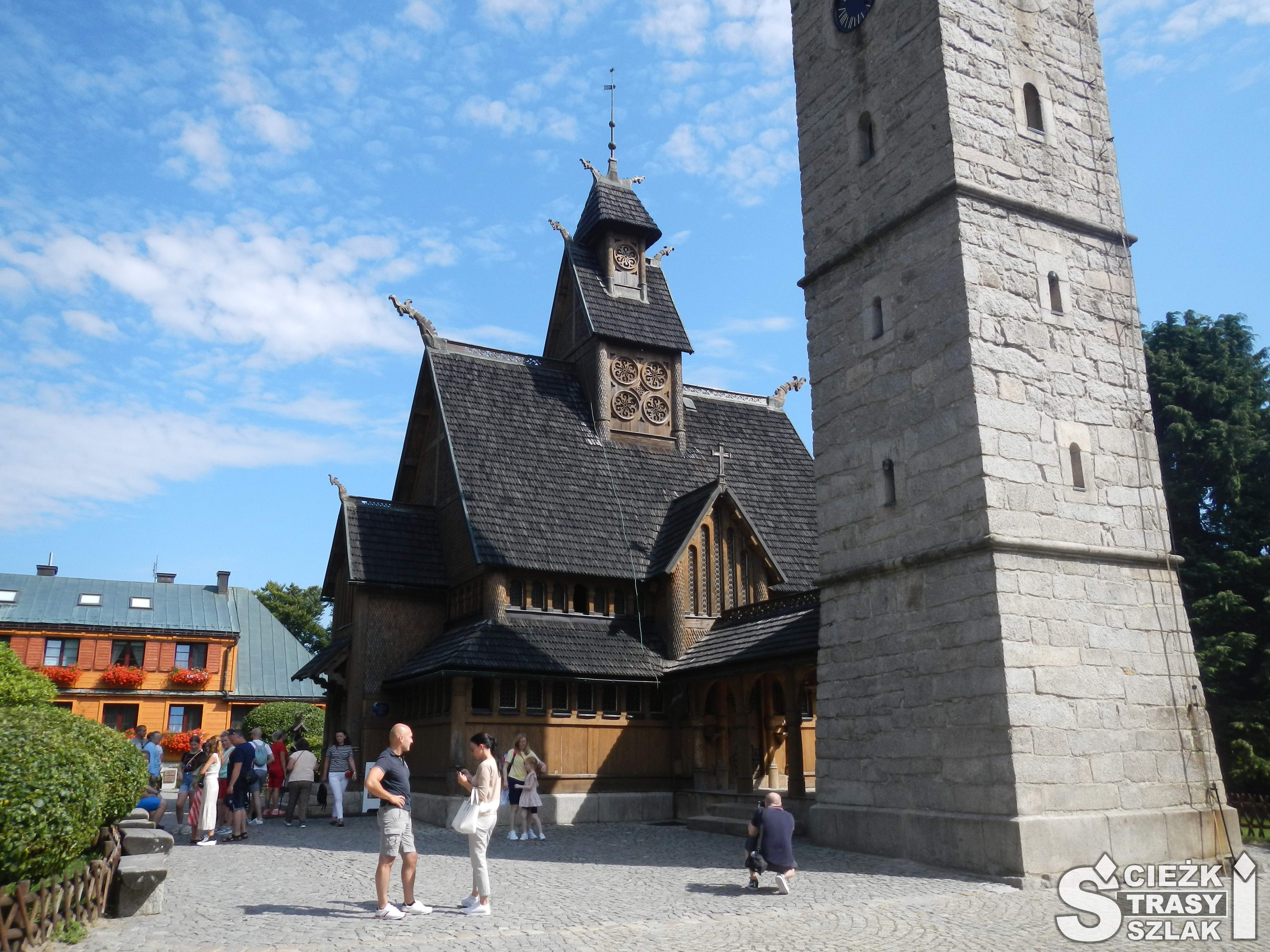 Zabytkowy kościół drewniany osłonięty przed górskim klimatem przez wysoką dzwonnicę podziwiany przez dorosłych