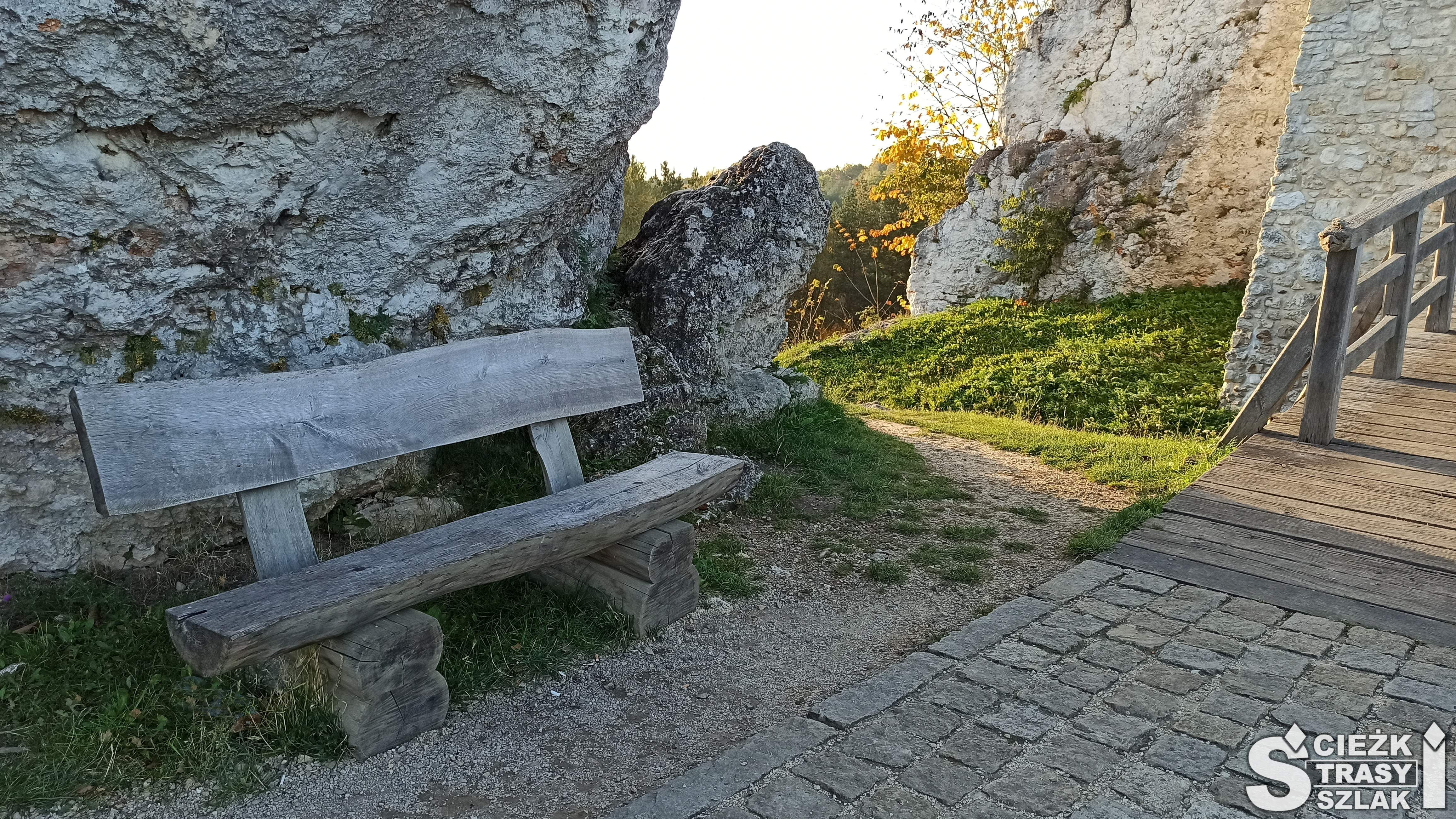Ścieżka przy wejściu do Zamku Bobolice z drewnianą ławką opartą o wapienną skałę na szlaku Orlich Gniazd