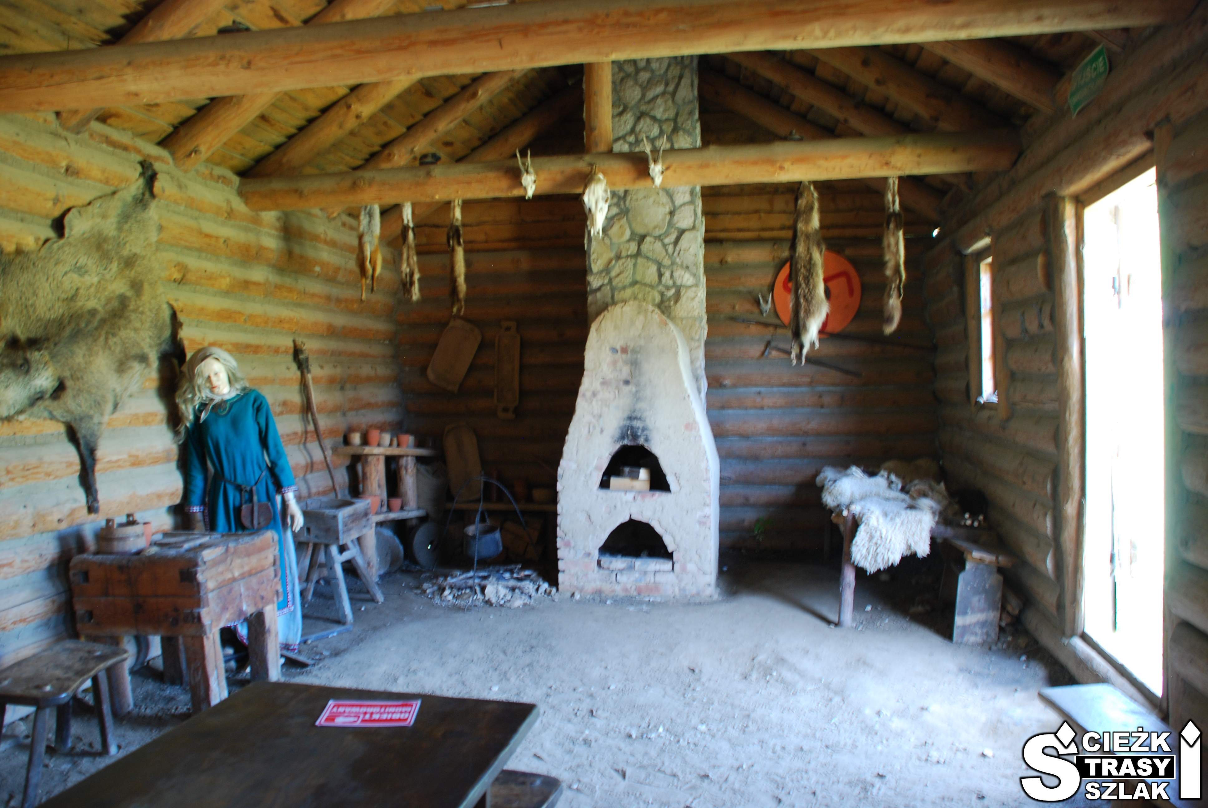 Drewniane i surowe wnętrze chaty wodza z wąskim, wysokim kominkiem i piecem chlebowym w Grodzie Birów