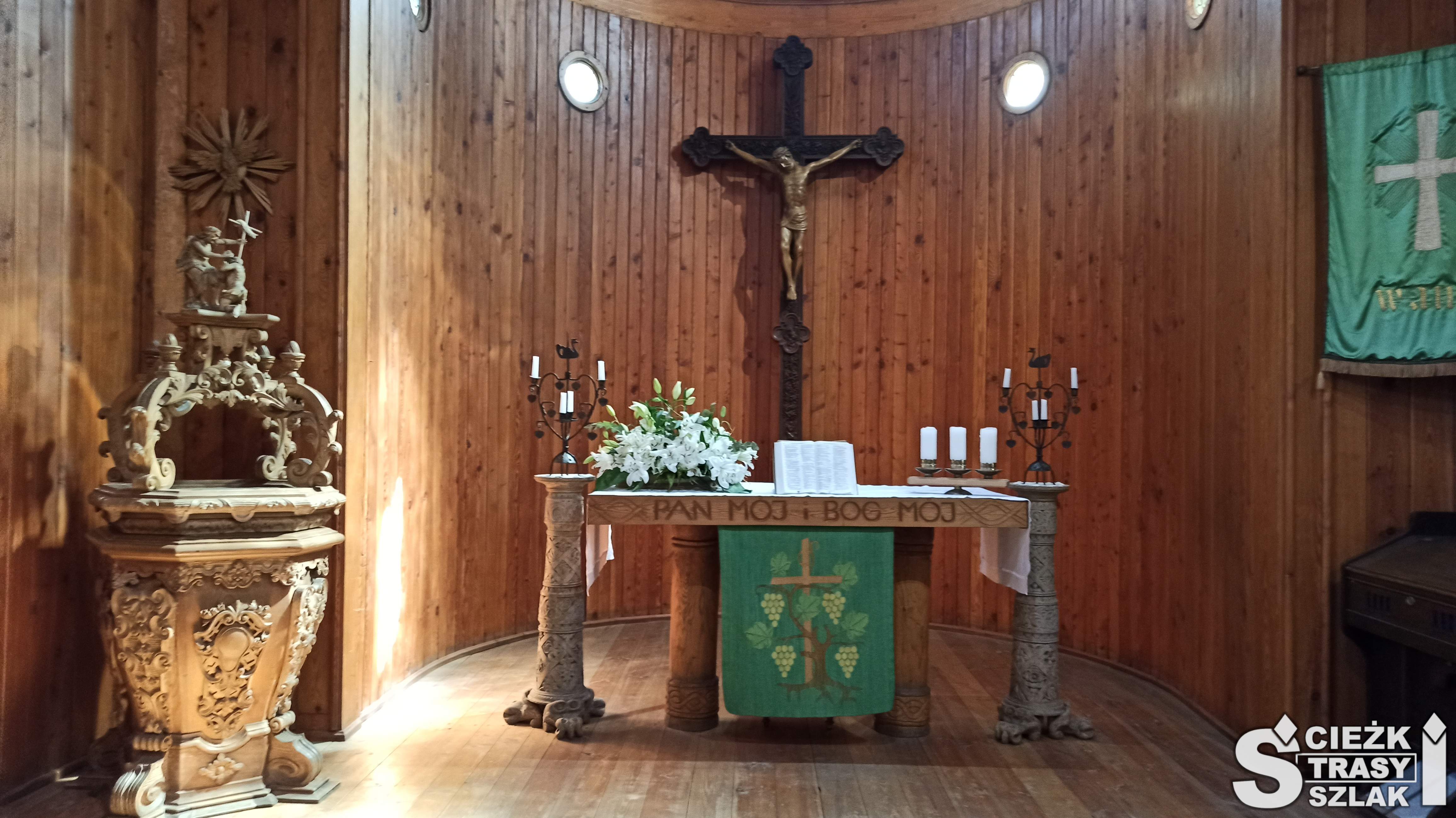 Dwa świeczniki z symboliką szczęśliwych małżeństwa na ołtarzu z krzyżem Jakuba z Janowic przy chrzcielnicy