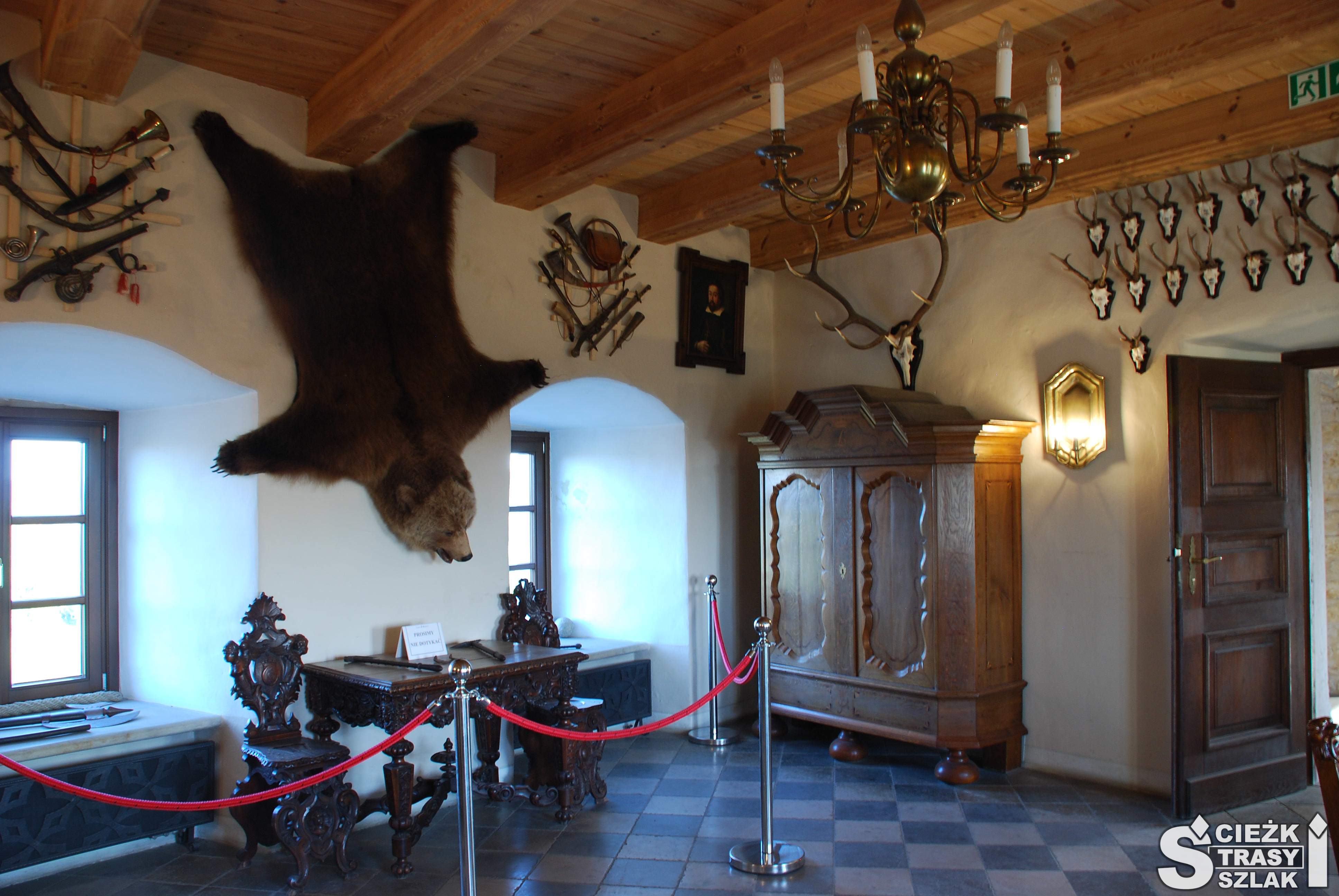 Komnata Zamku Bobolice z trofeami myśliwskimi zawieszonymi na ścianie  w postaci wypchanego niedźwiedzia i rogów