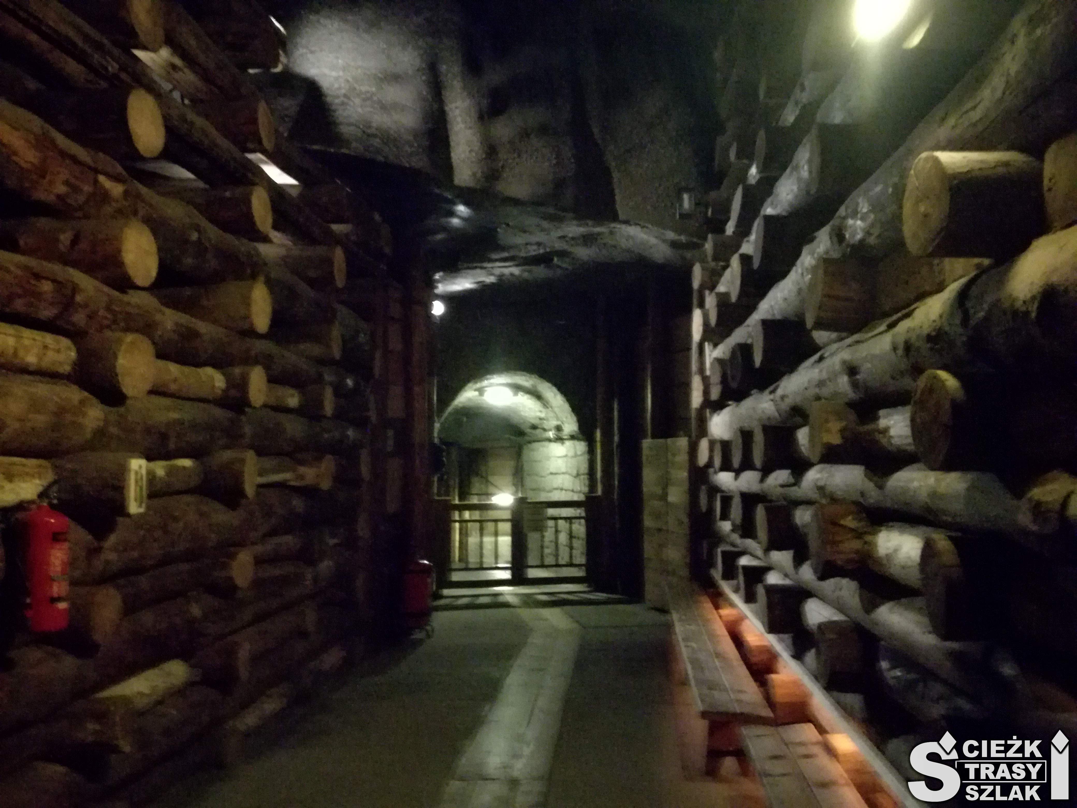 Długi i wysoki korytarz górniczy w kopalni soli w Wieliczce wzmocniony ściankami z drewnianych bali