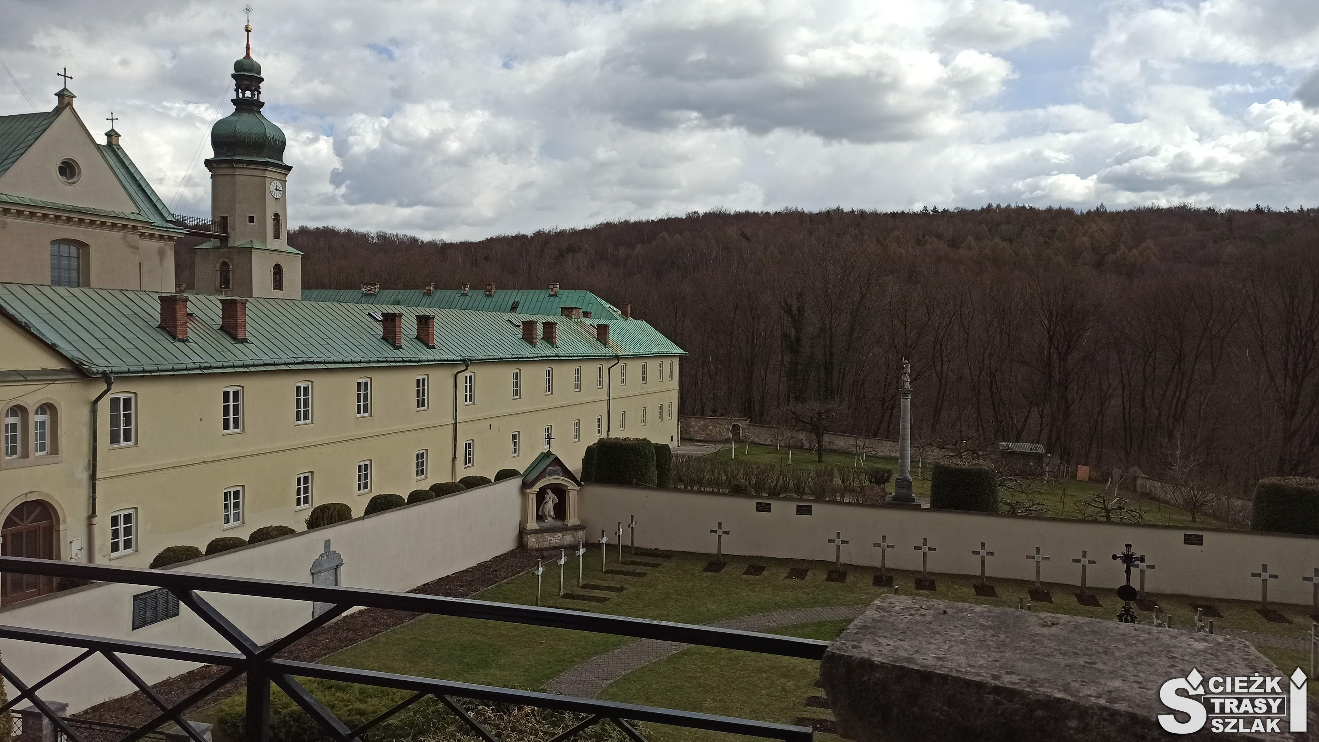 Bok budynku klasztornego karmelitów graniczącego z cmentarzem na którym stoi żelazny krzyż