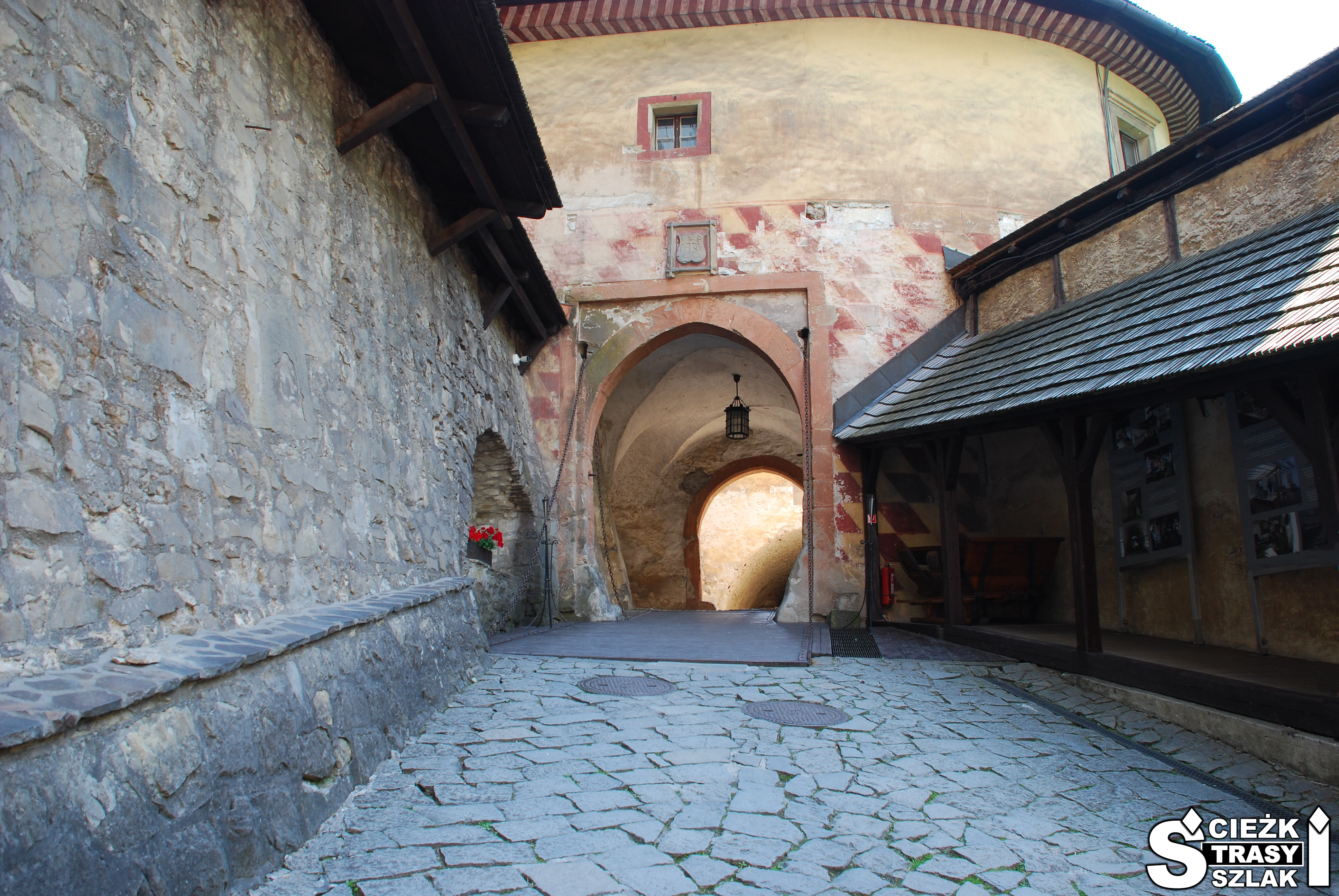 Kamienna droga wzdłuż ścian z kamienia prowadząca do łukowatego wejścia na dziedziniec Zamku Orawskiego na Słowacji