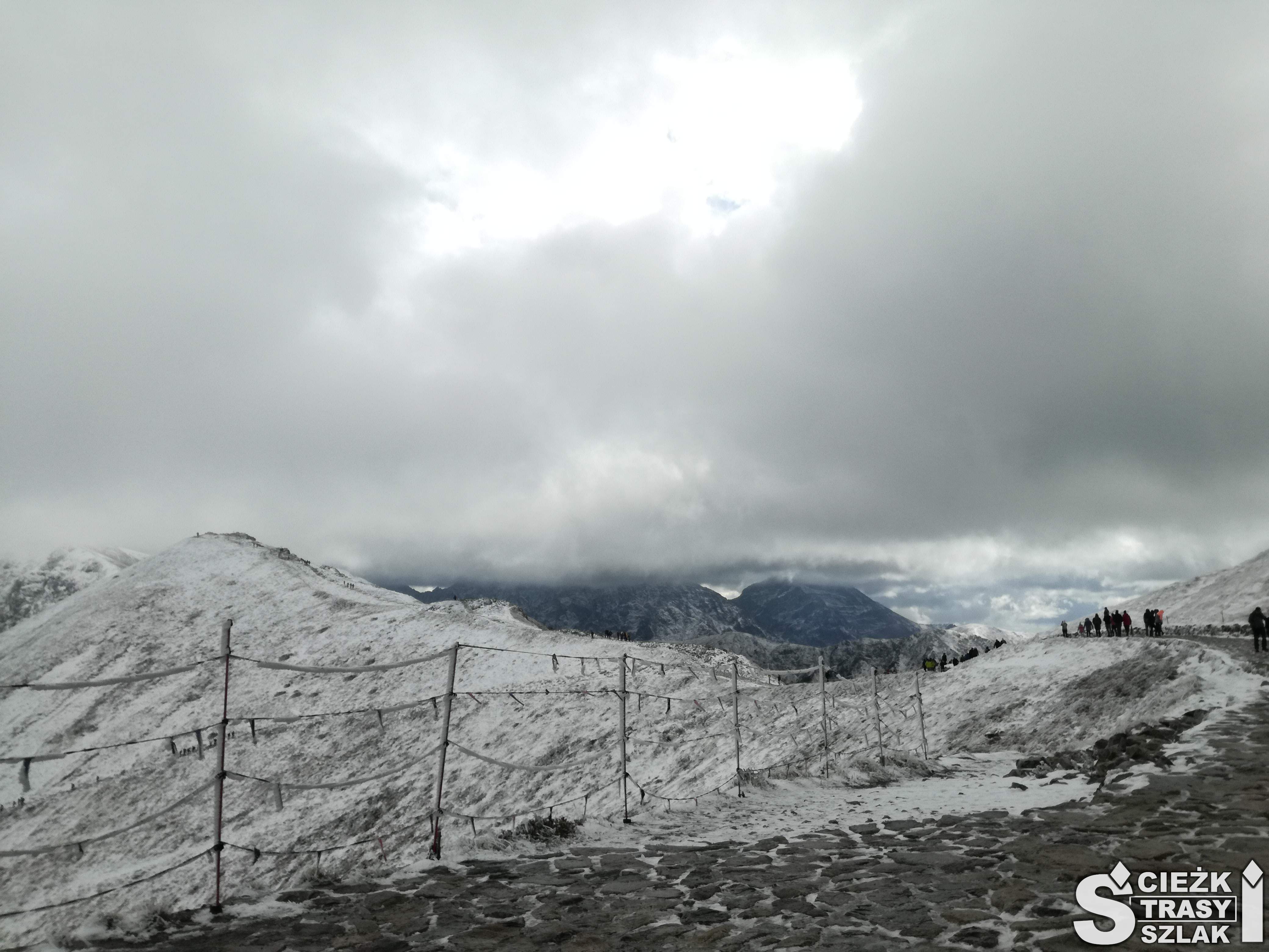 Szlaki górskie wytyczone linowym ogrodzeniem przez pokryte śniegiem góry na szczycie Kasprowy Wierch