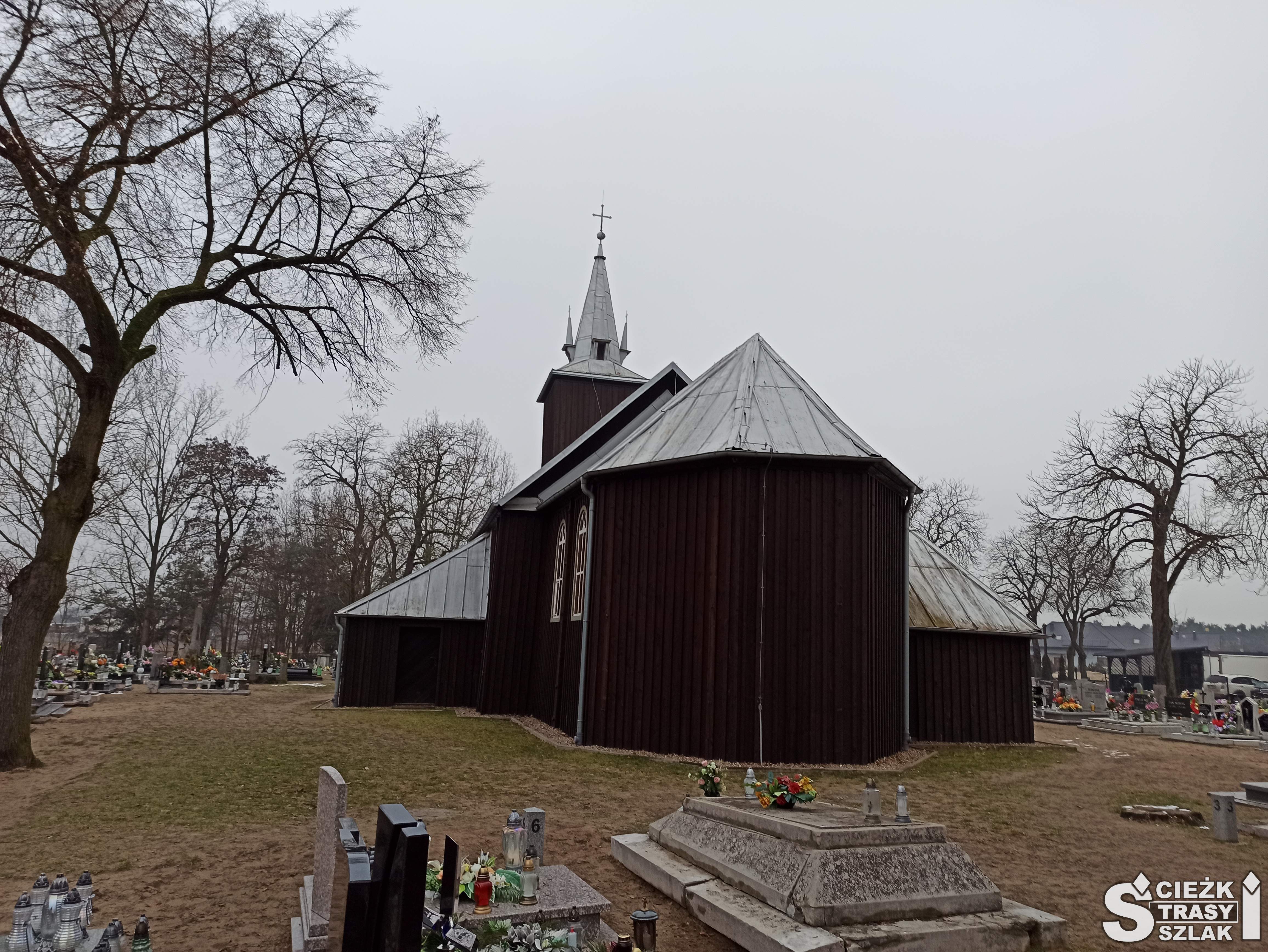 Wyokrąglone prezbiterium z tyłu drewnianego kościoła na cmentarzu w Kębłowie
