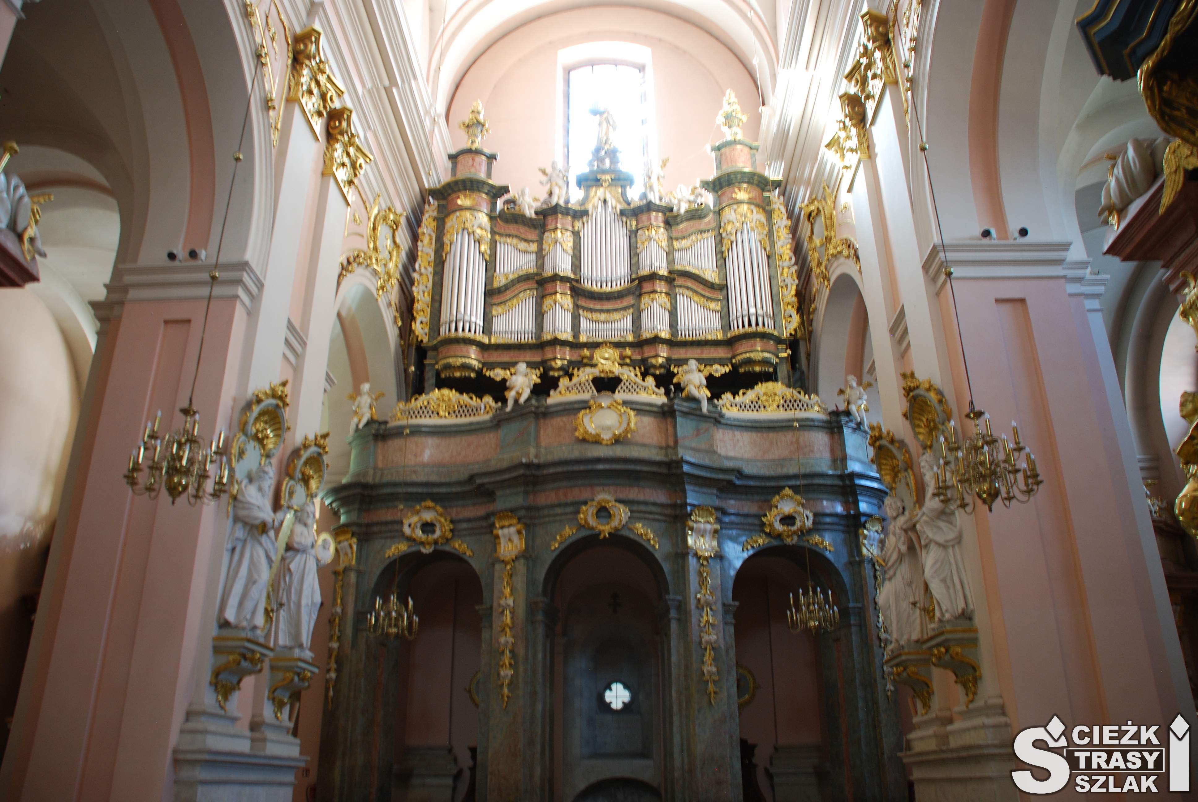Wysoko zamontowane organy kościelne ze złotymi zdobieniami we wnętrzu bazyliki w Miechowie z repliką Grobu Bożego