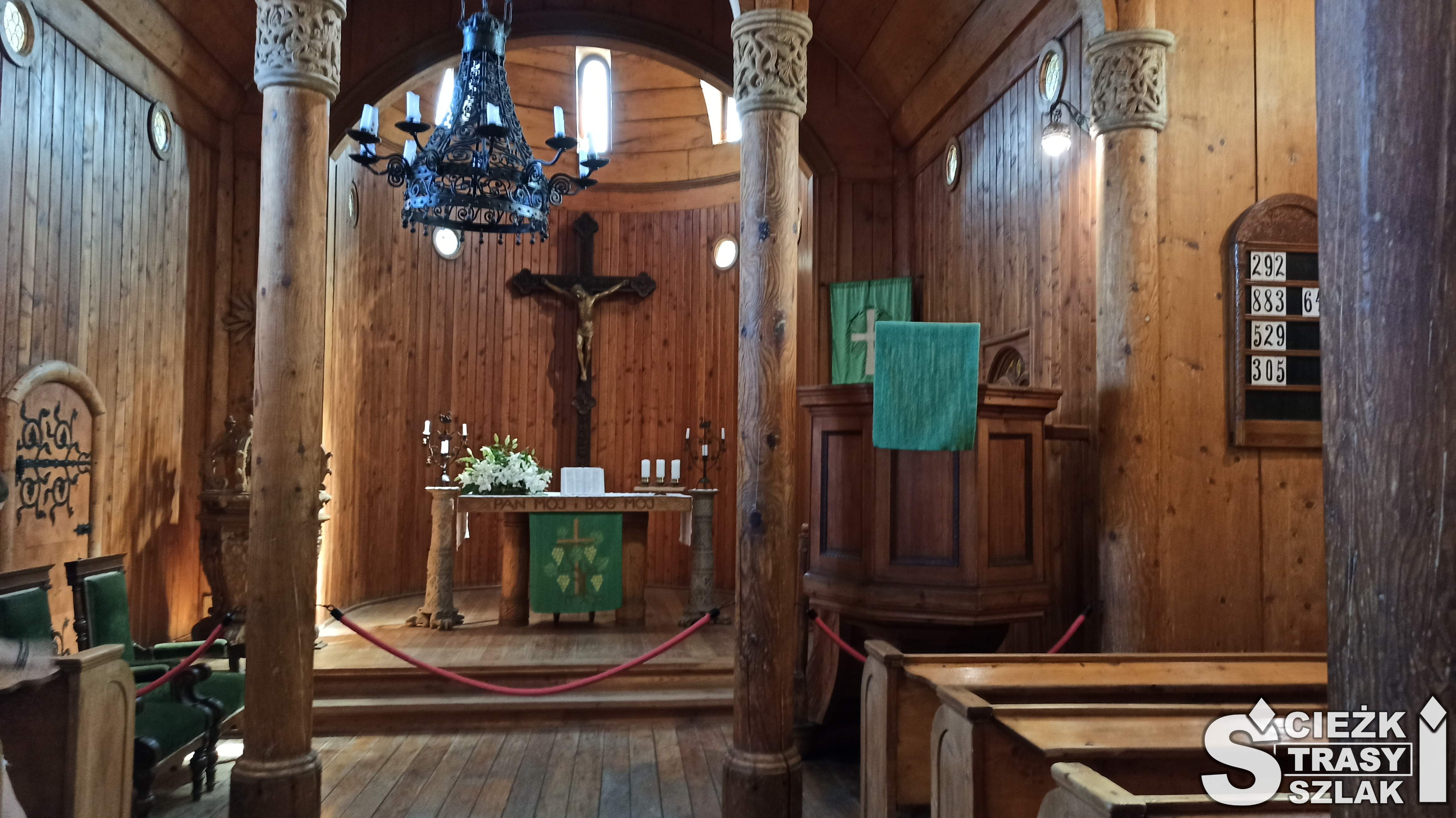 Dwie drewniane kolumny zdobione u samej góry scenami z biblii na tle ołtarza