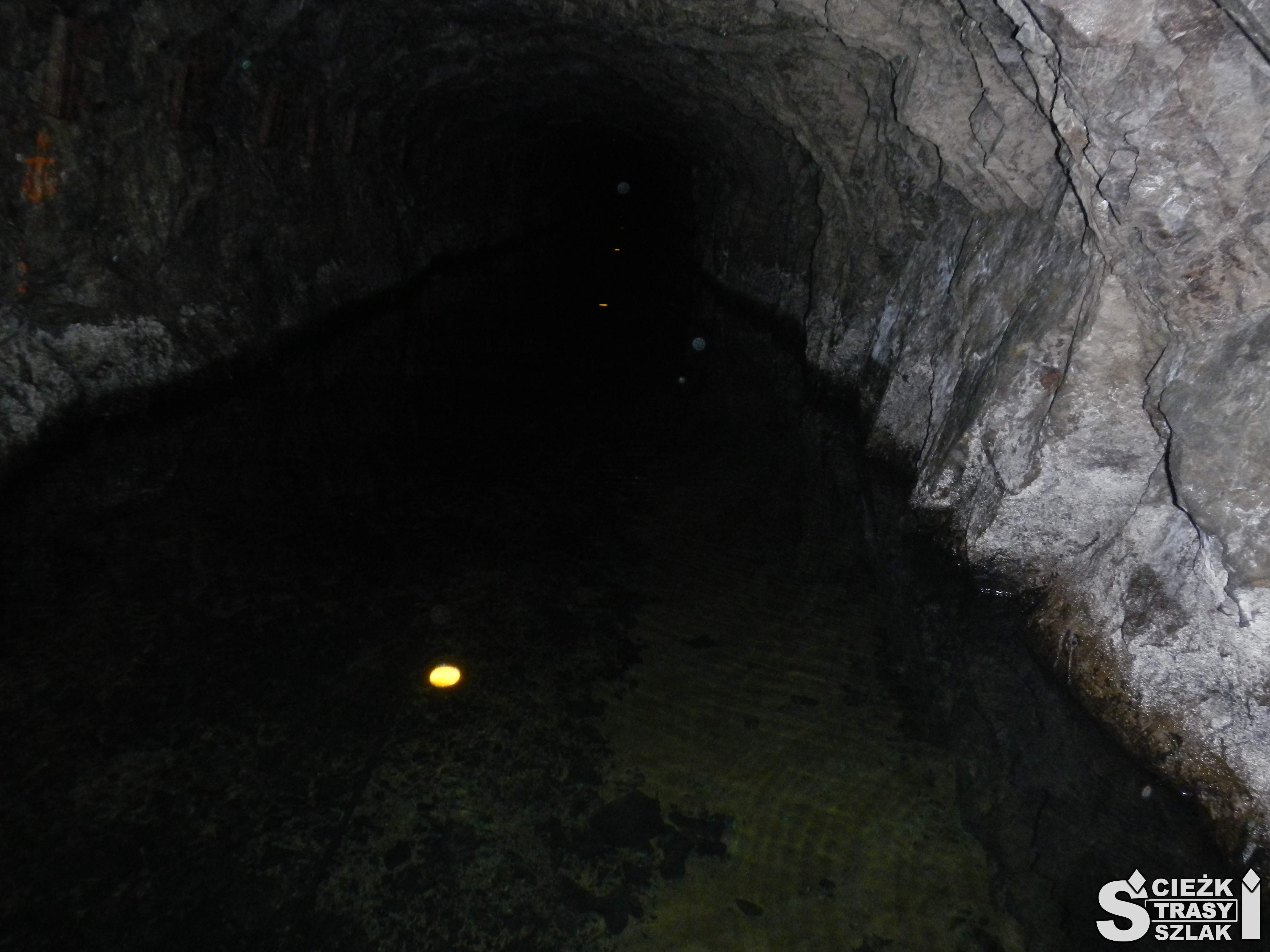 Nikłe punkty świetle wyznaczające trasę podziemnego spływu łodzią wąskim tunelem