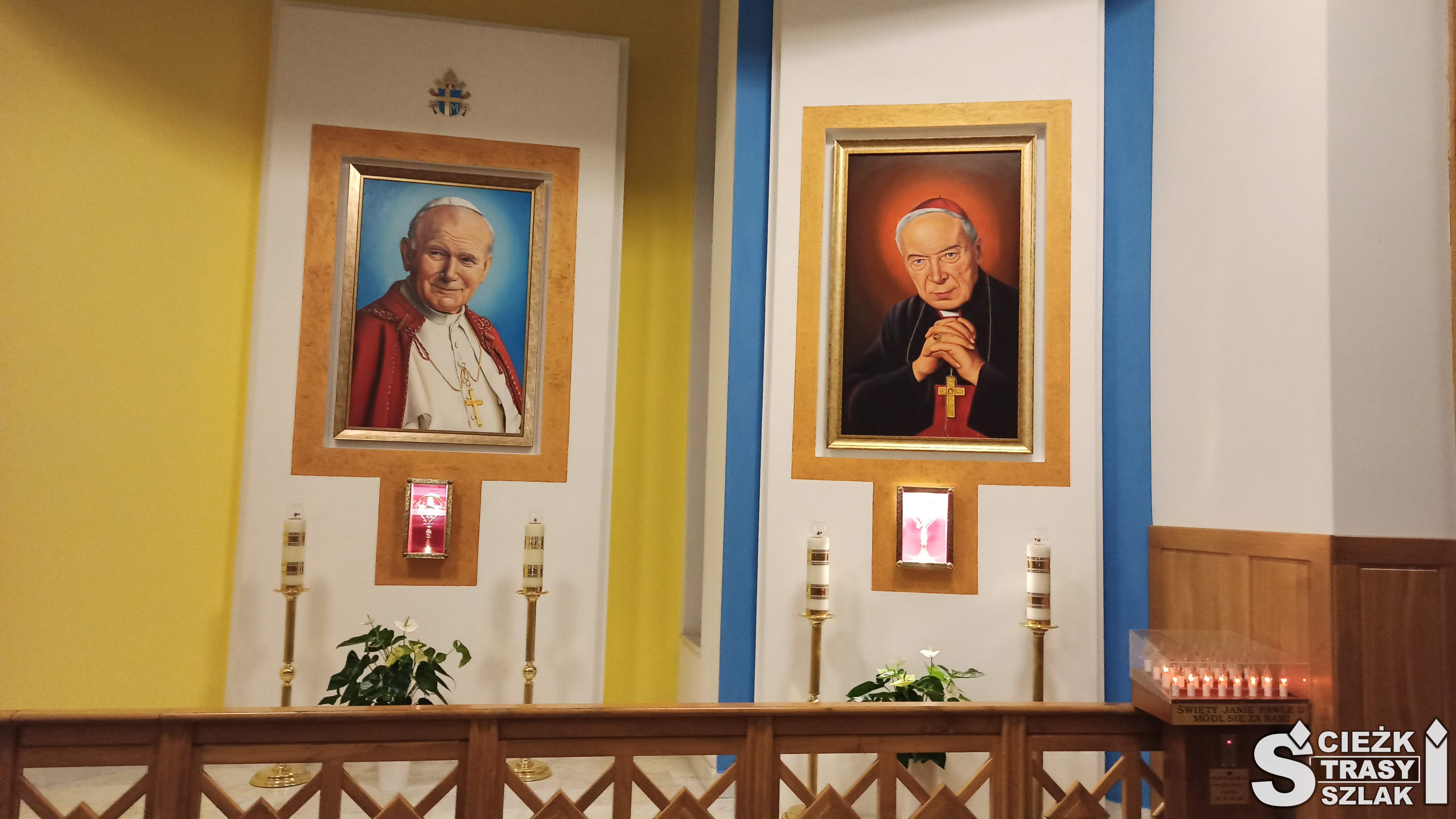 Obraz Jana Pawła II i kardynała na ścianie Sanktuarium w Jaworznie za świecami