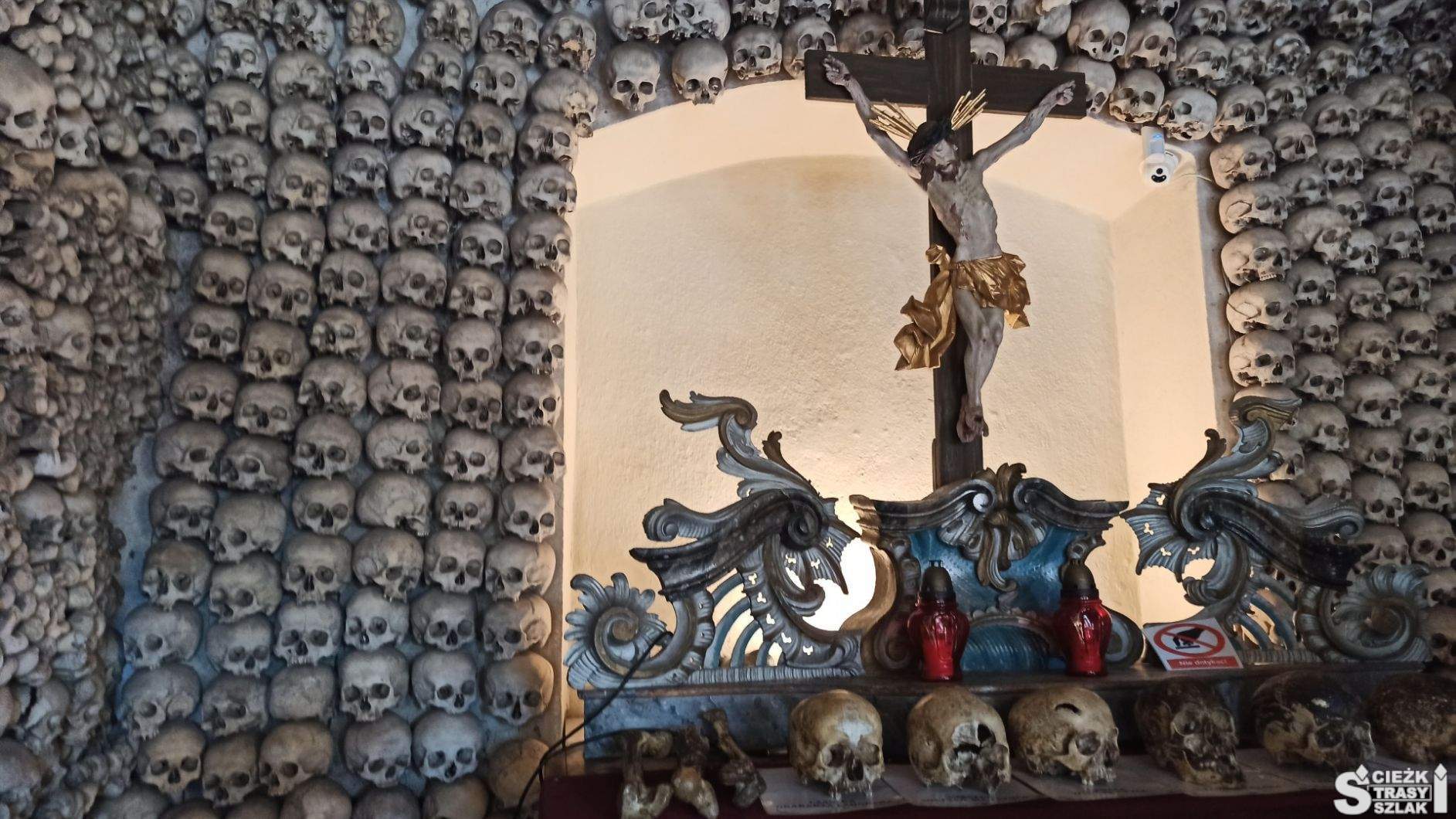 Ludzkie czaszki z historią przed krzyżem z Chrystusem na ołtarzu skupiającym wzrok tysięcy czaszek