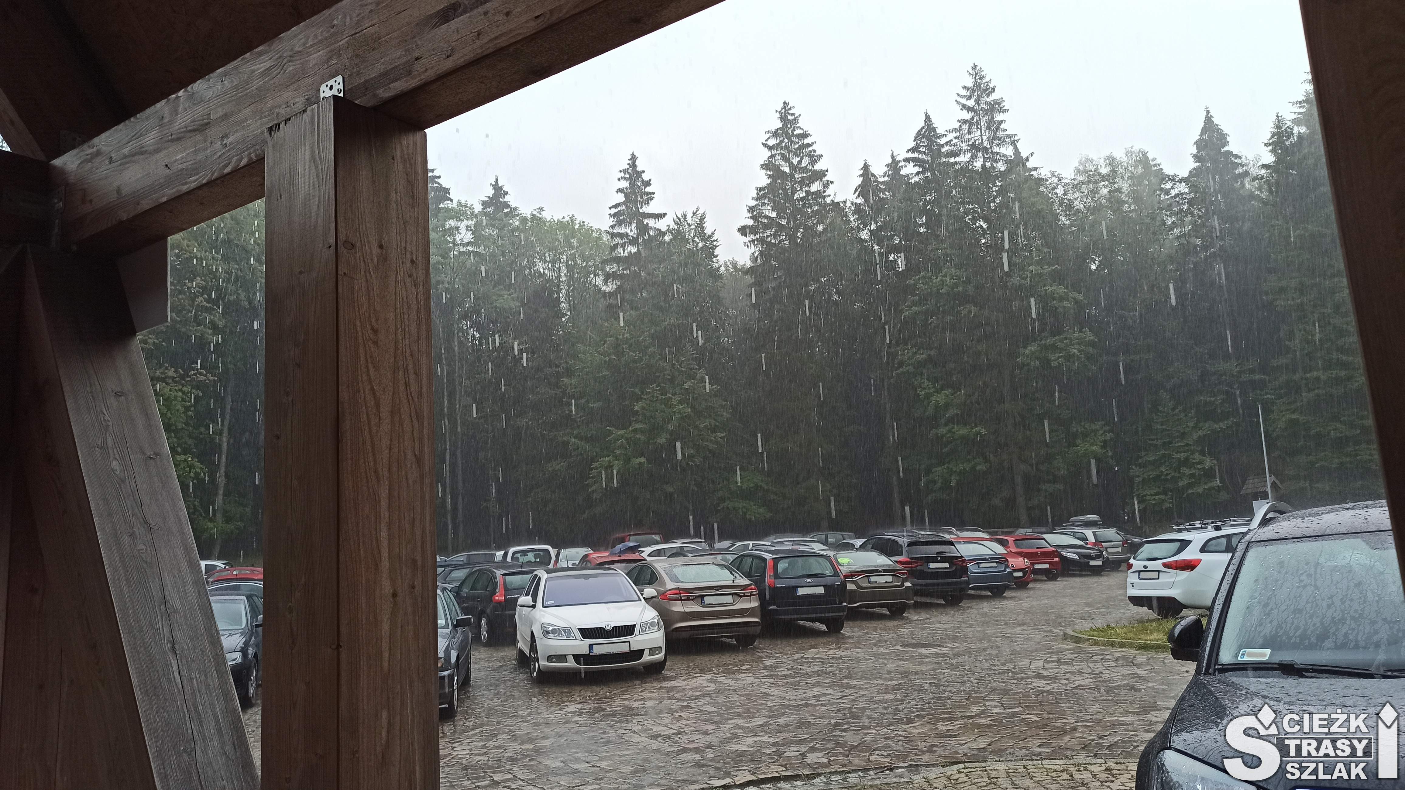 Drewniana wiata i samochody w deszczu na parkingu YMCA