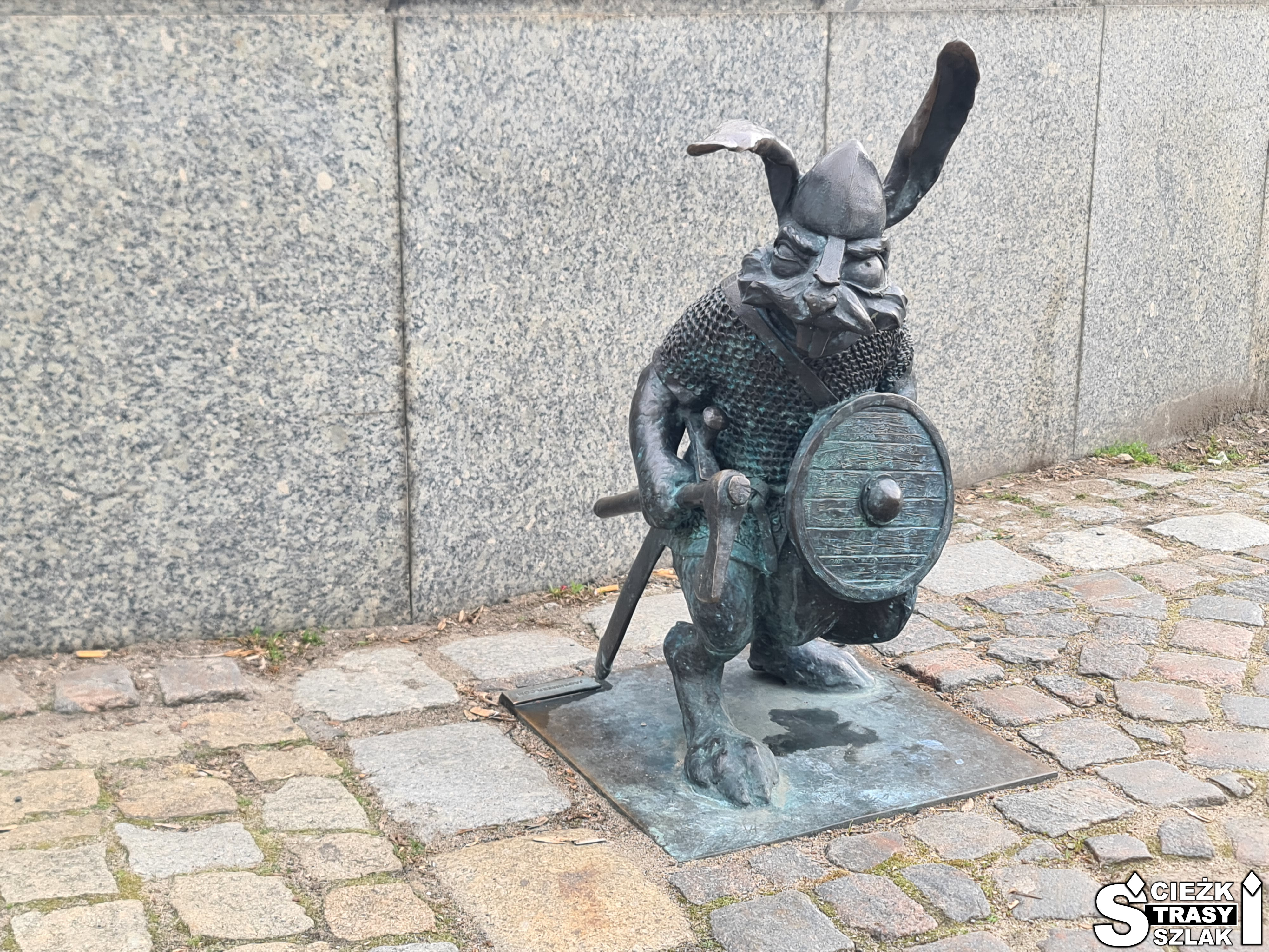 Figurka królika prezentująca Piastowskiego Woja z tarczą przytwierdzona do chodnika w Gnieźnie