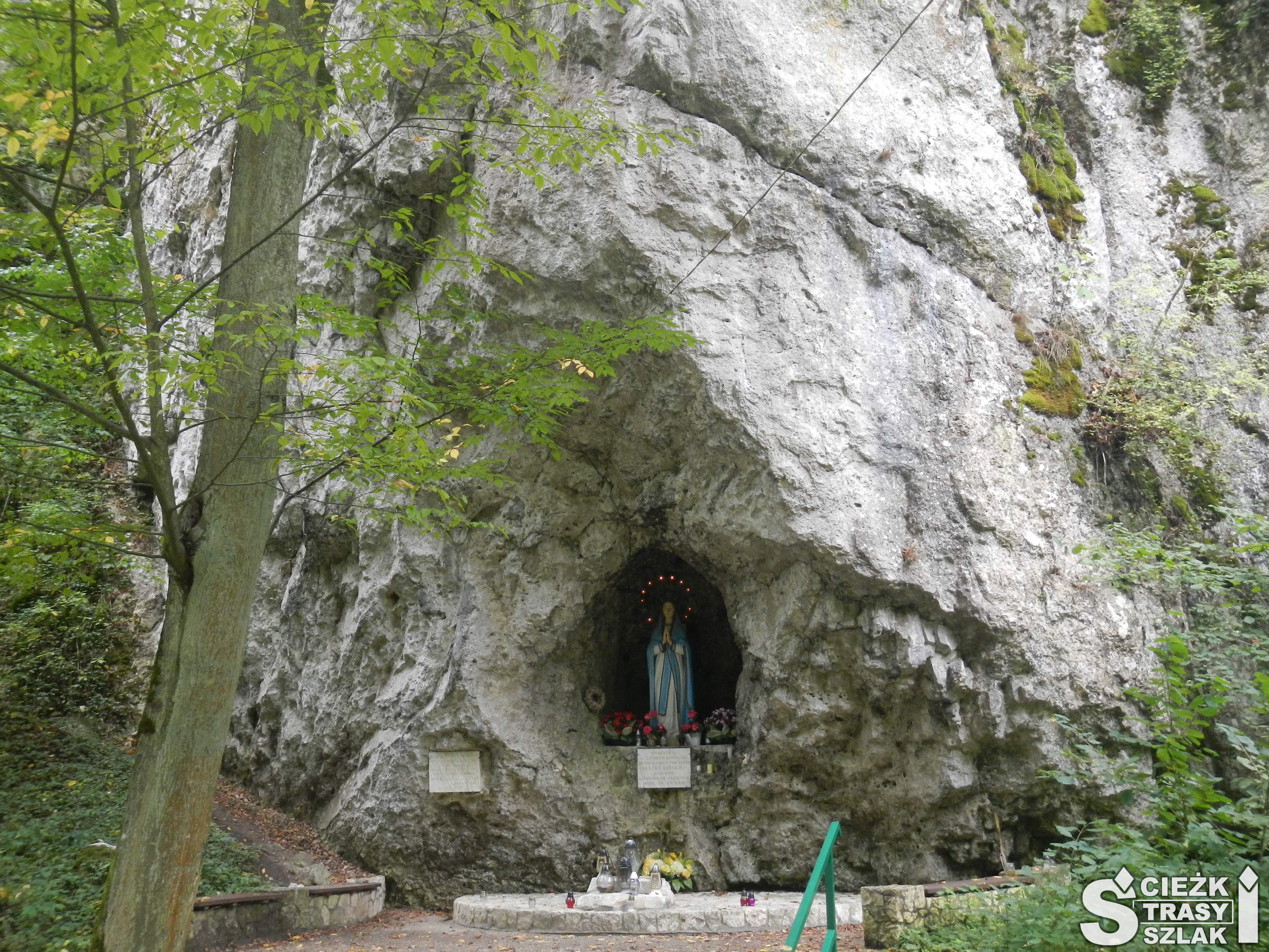 Dwie tablice pamiątkowe przy figurze Matki Boskiej wstawionej do wnęki skały wapiennej