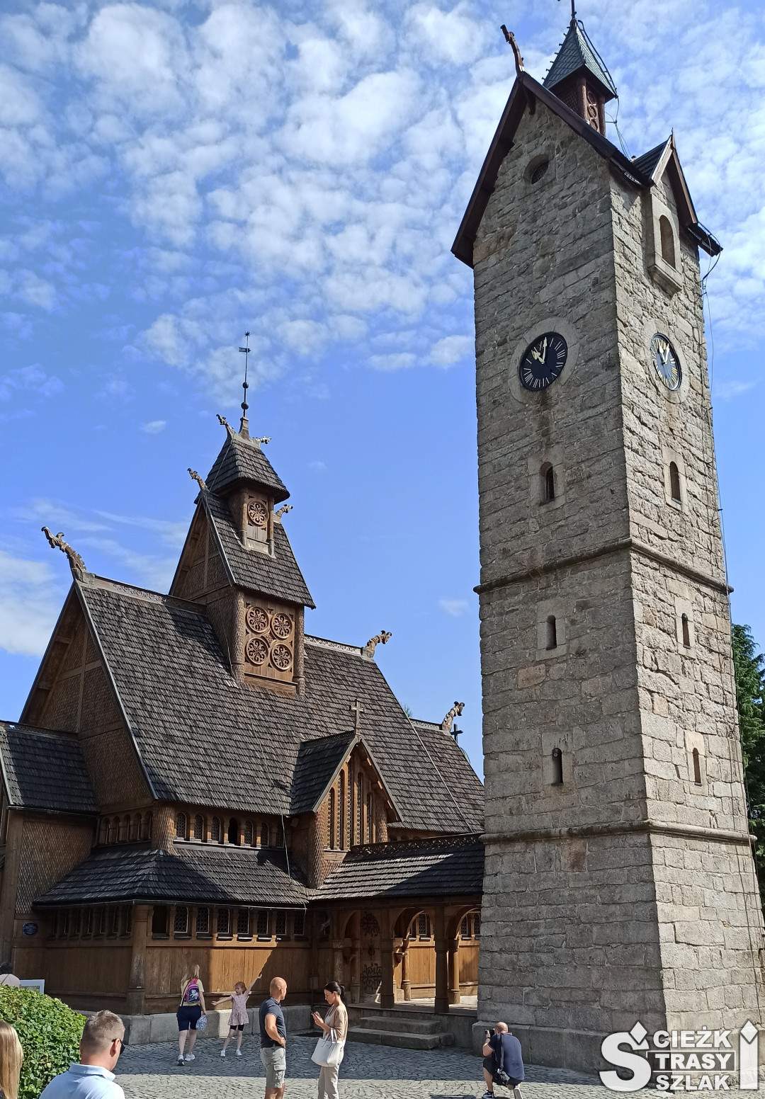 Wysoka kamienna dzwonnica chroniąca drewniany kościół ewangelicki w Karpaczu latem