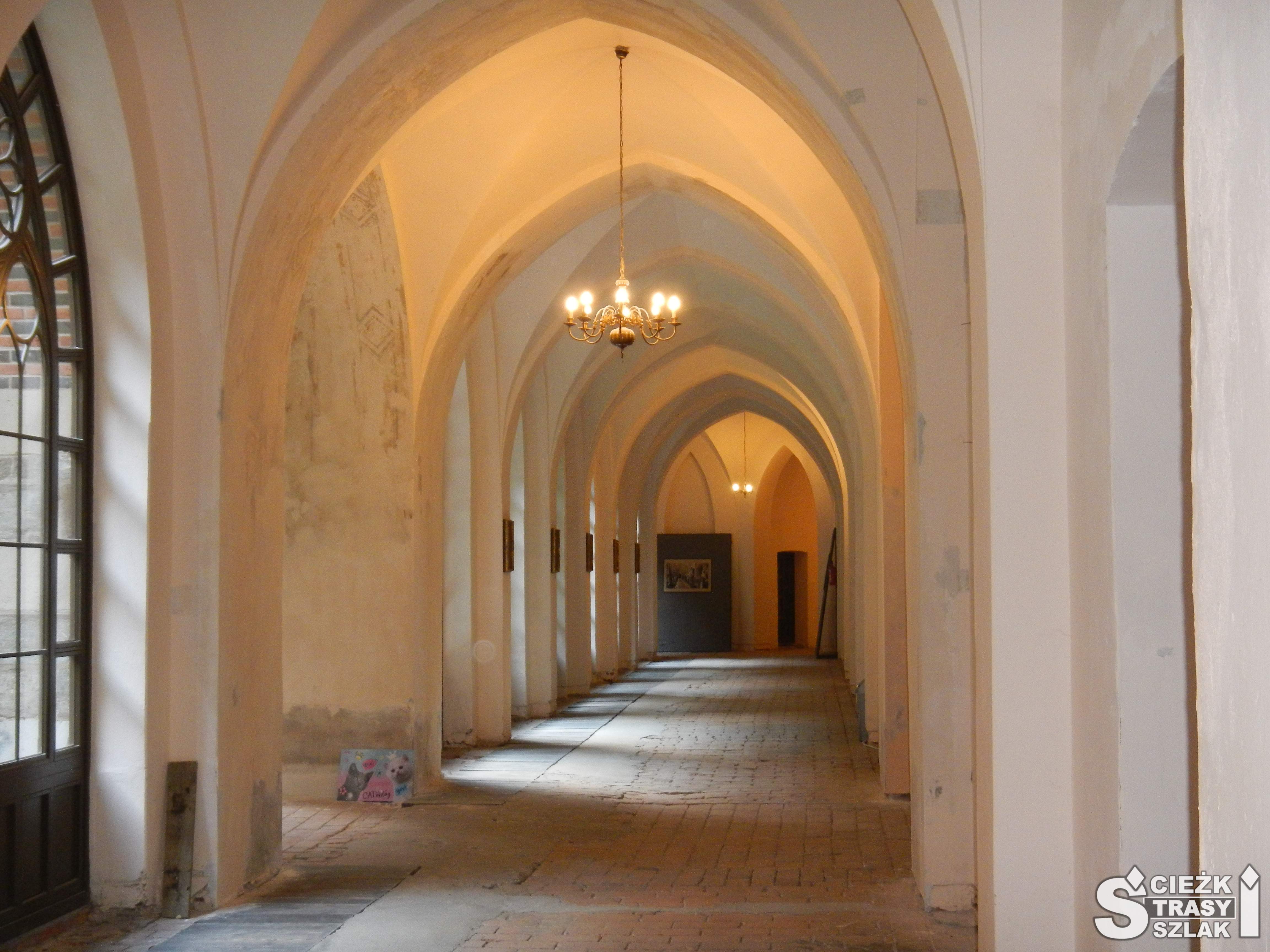 Łukowe sklepienia pokryte jasnym tynkiem tworzące długi korytarz w środku Pałacu Marianny Orańskiej