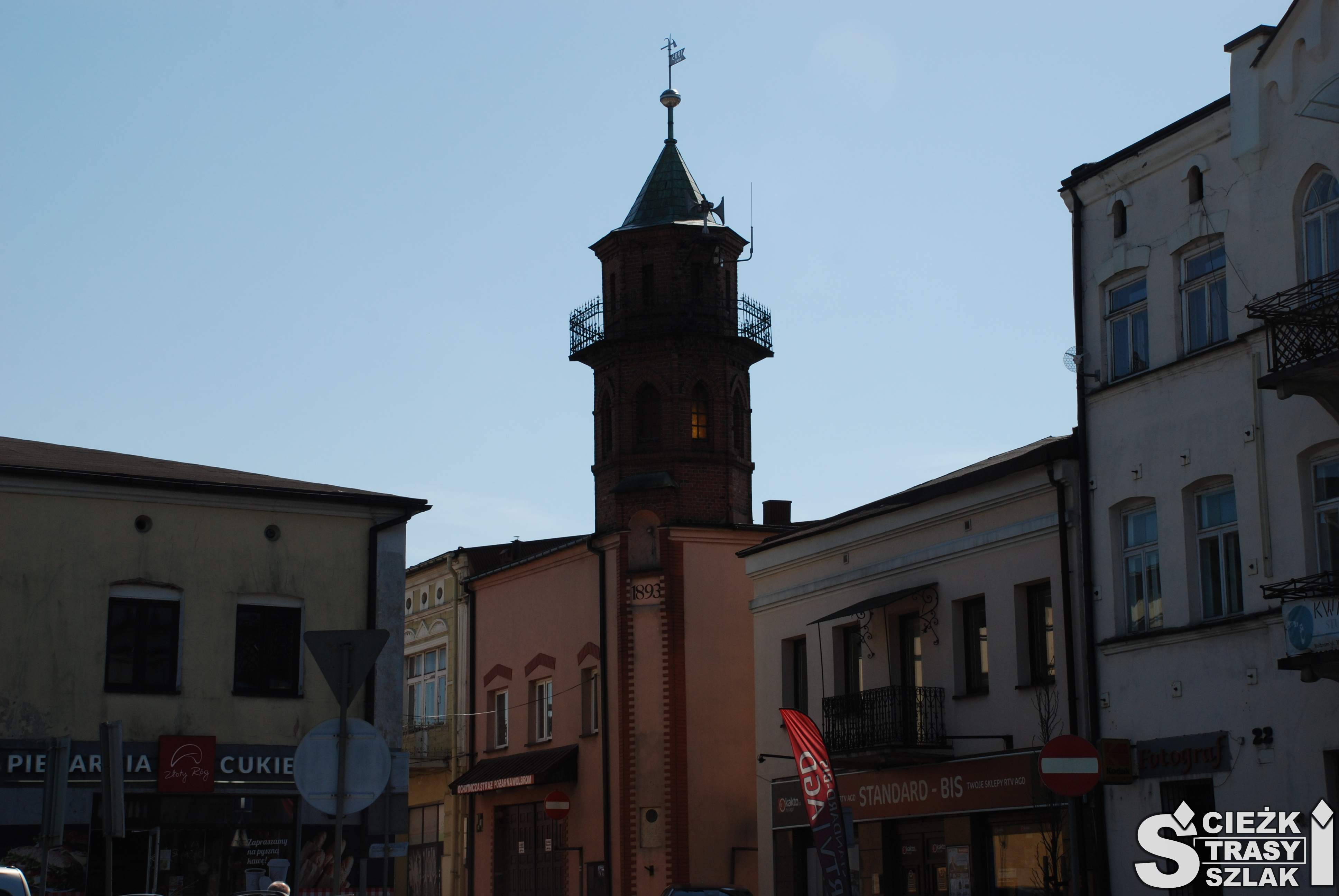 Stara wieża w stylu neogotyckim wznosząca się nad remizą strażacką i starymi kamienicami blisko rynku w Wolbromiu