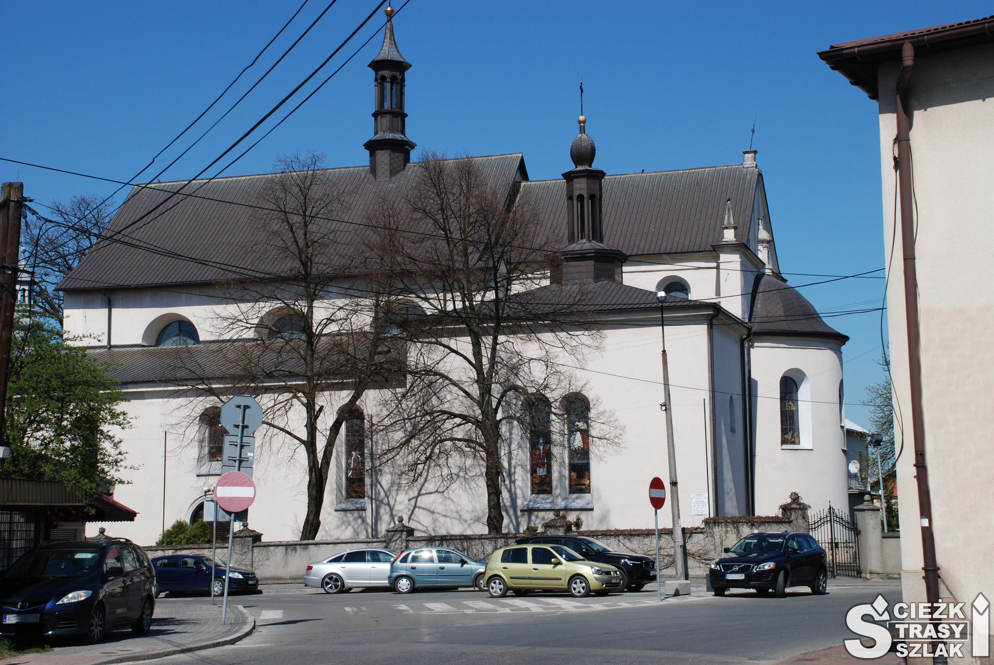Kościół Św. Katarzyny w Wolbromiu z białą elewacją i wyokrąglonym prezbiterium z tyłu przy rynku