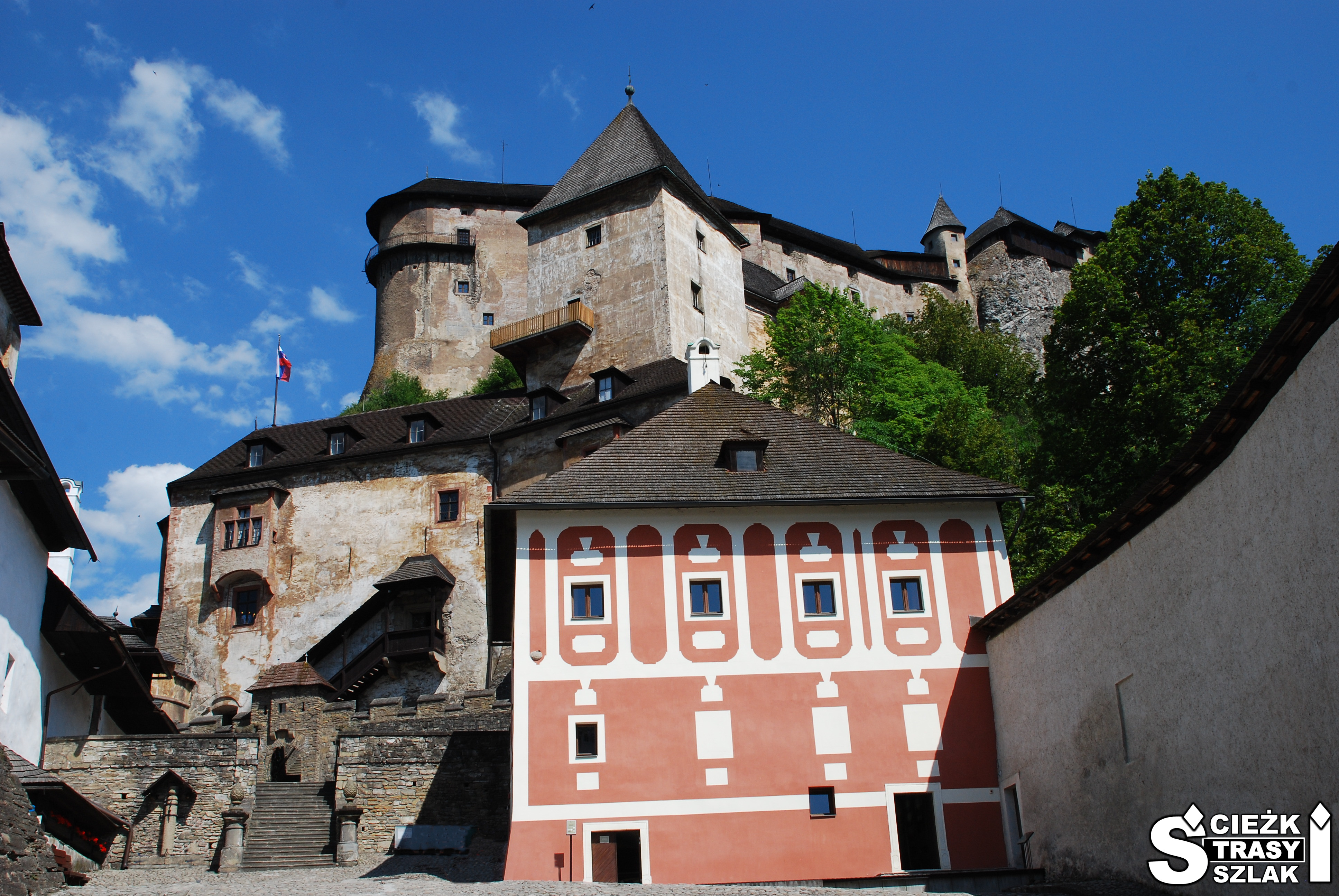 Pałac Turzo na dziedzińcu przy dolnym Zamku Orawskim na Słowacji z Zamkiem Górnym na skale w tle