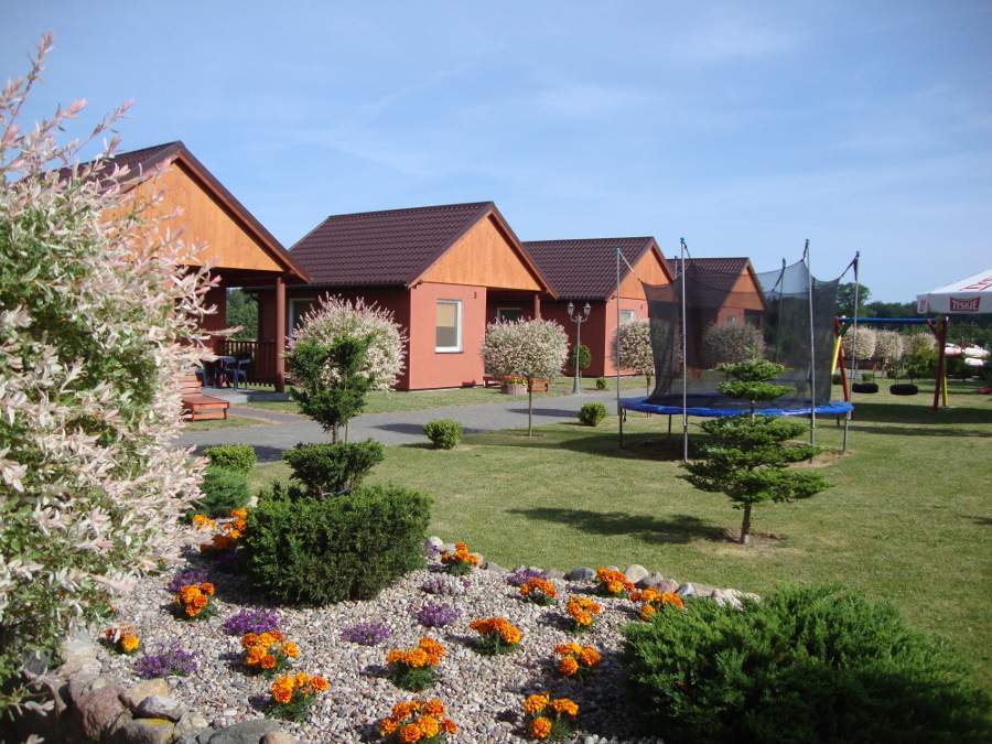 Zdjęcie przedstawia cały obiekt z widokiem na cztery domki oraz trampolinę.