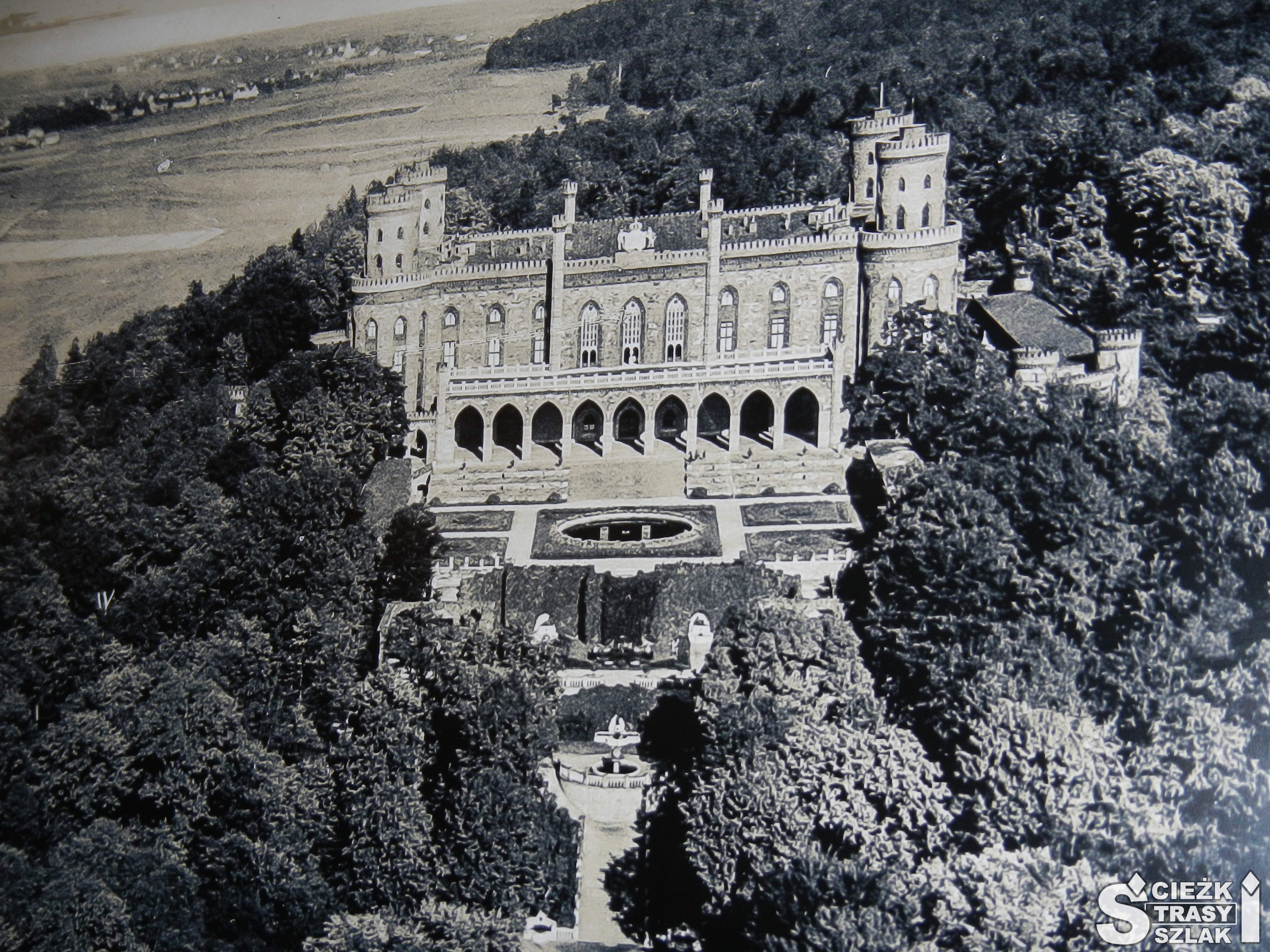 Czrno-biała ilustracja ukazująca Pałac Marianny Orańskiej w otoczeniu wysokich koron drzew na Dolnym Śląsku