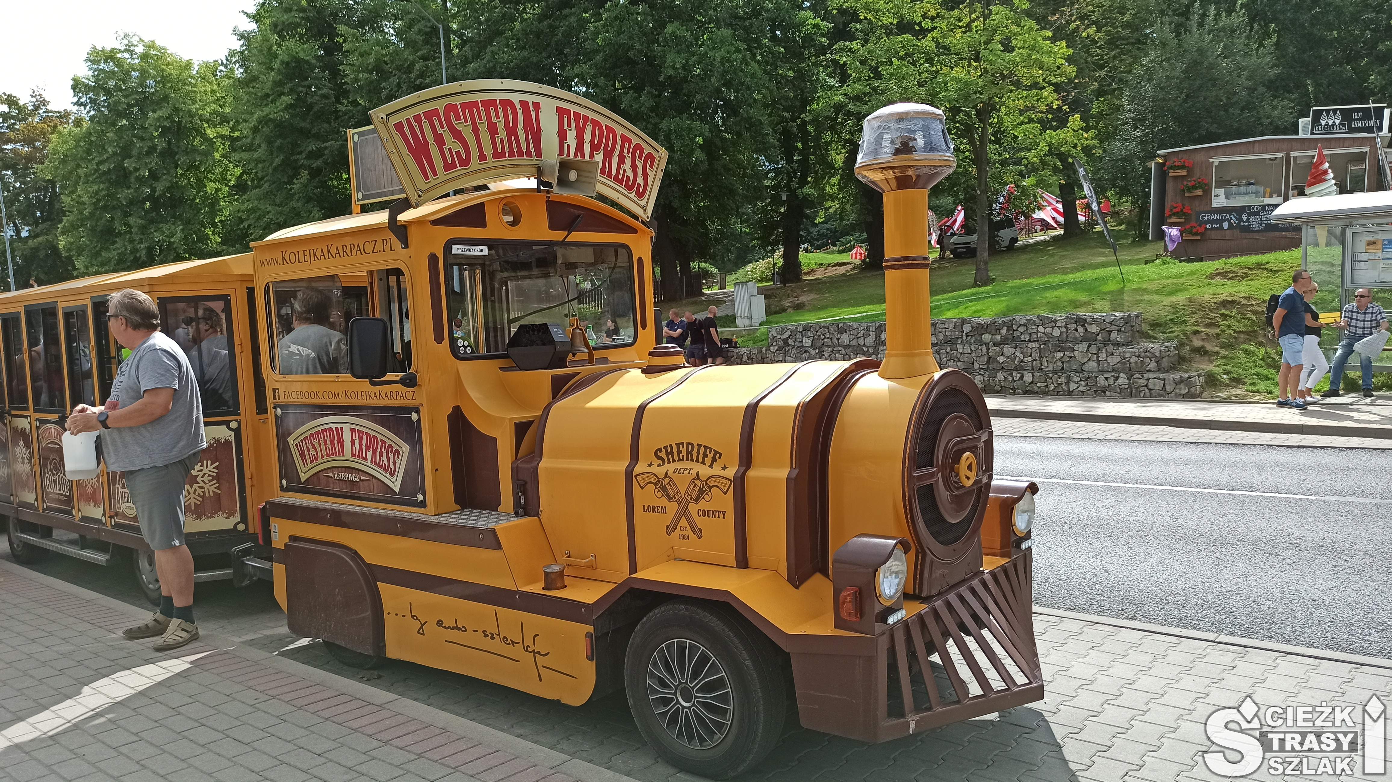 Kolejka turystyczna na kołach Western Express mknąca ulicami miasta Karpacz z dziećmi i dorosłymi