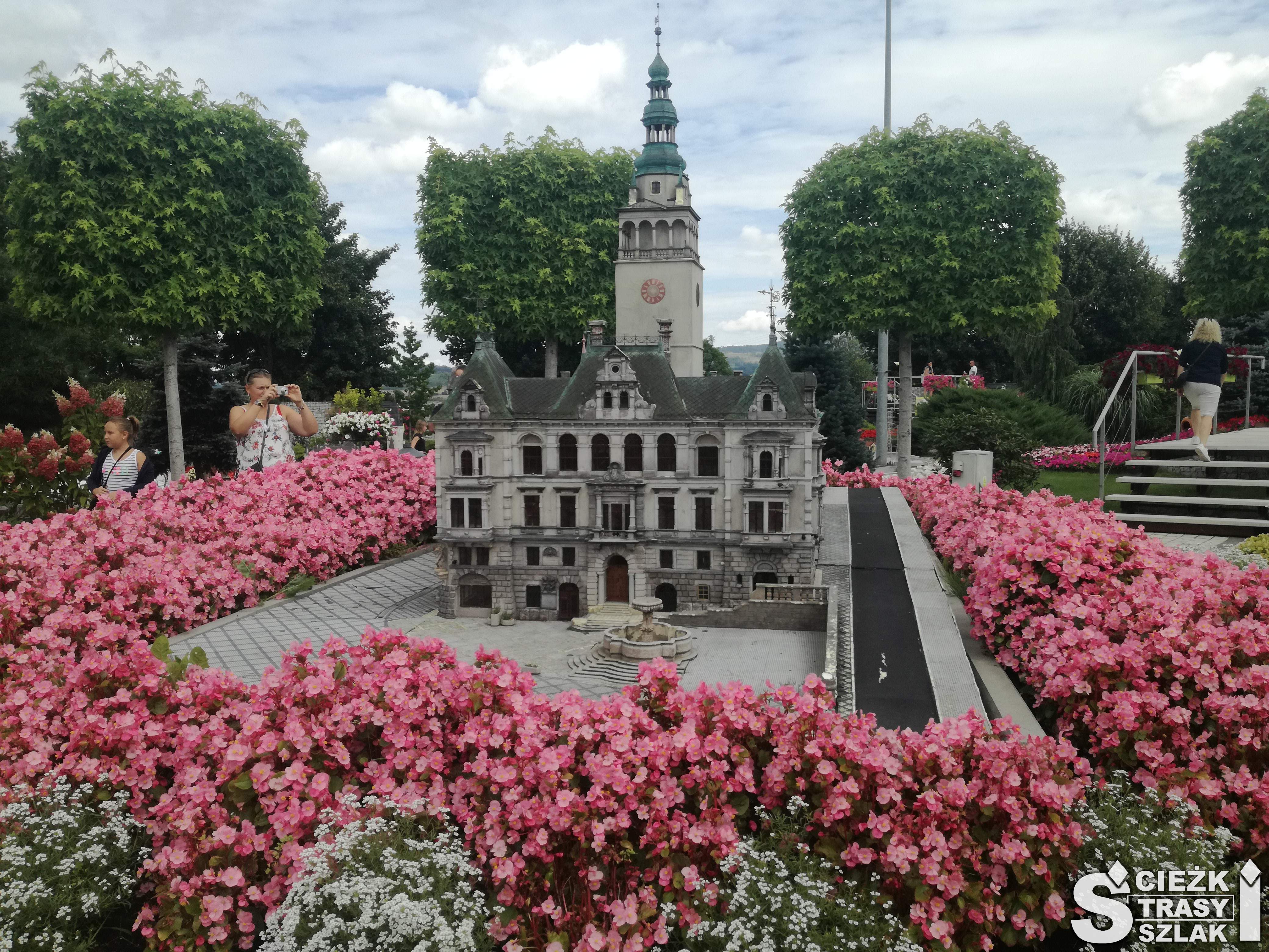 Miniatura kościoła Franciszkanów otoczona różowymi kwiatami i drzewami w tle z Parku Miniatur Minieuroland