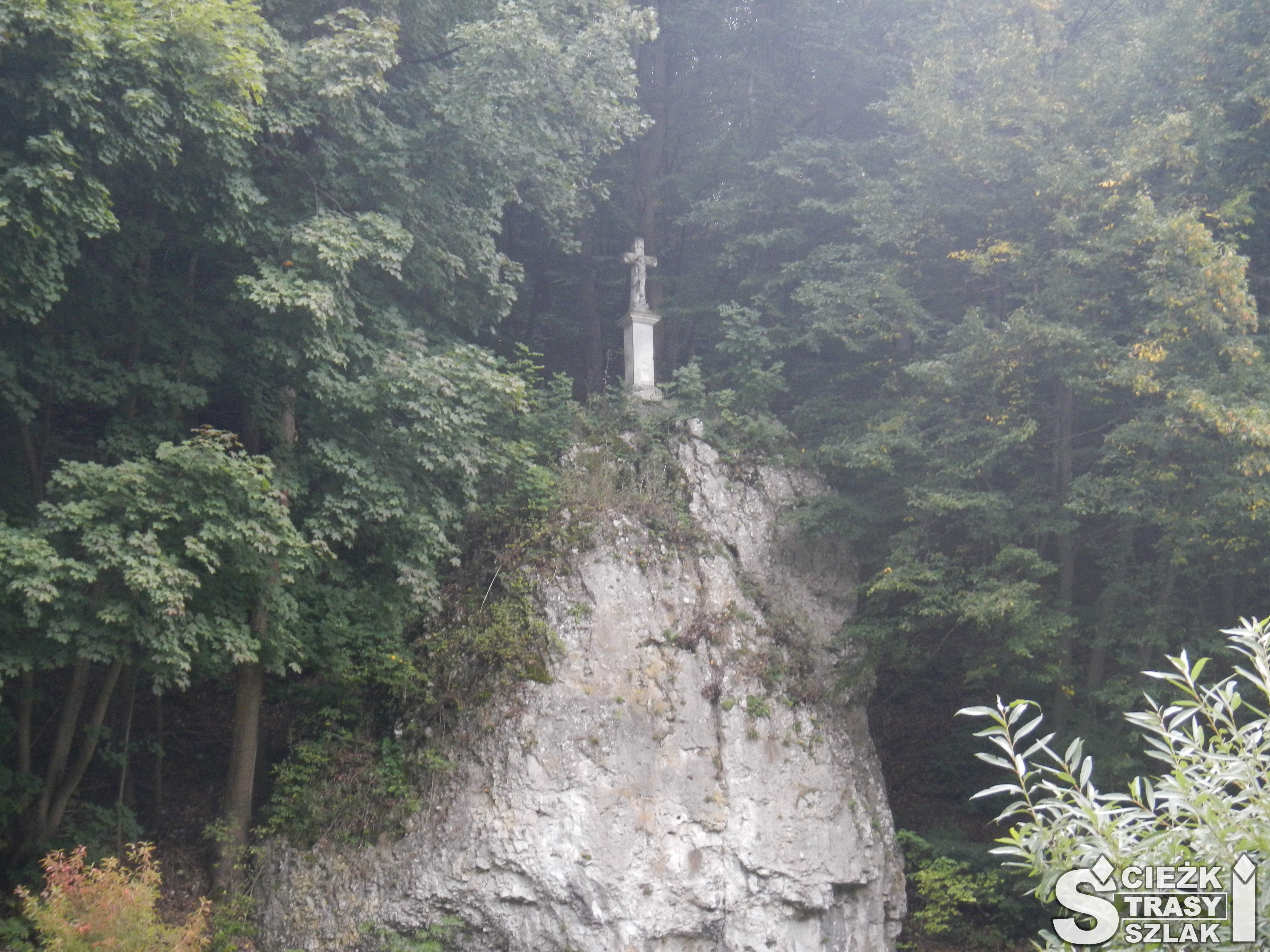 Kamienny krzyż na murowanej kolumnie wzniesiony na skale wapiennej wśród drzew