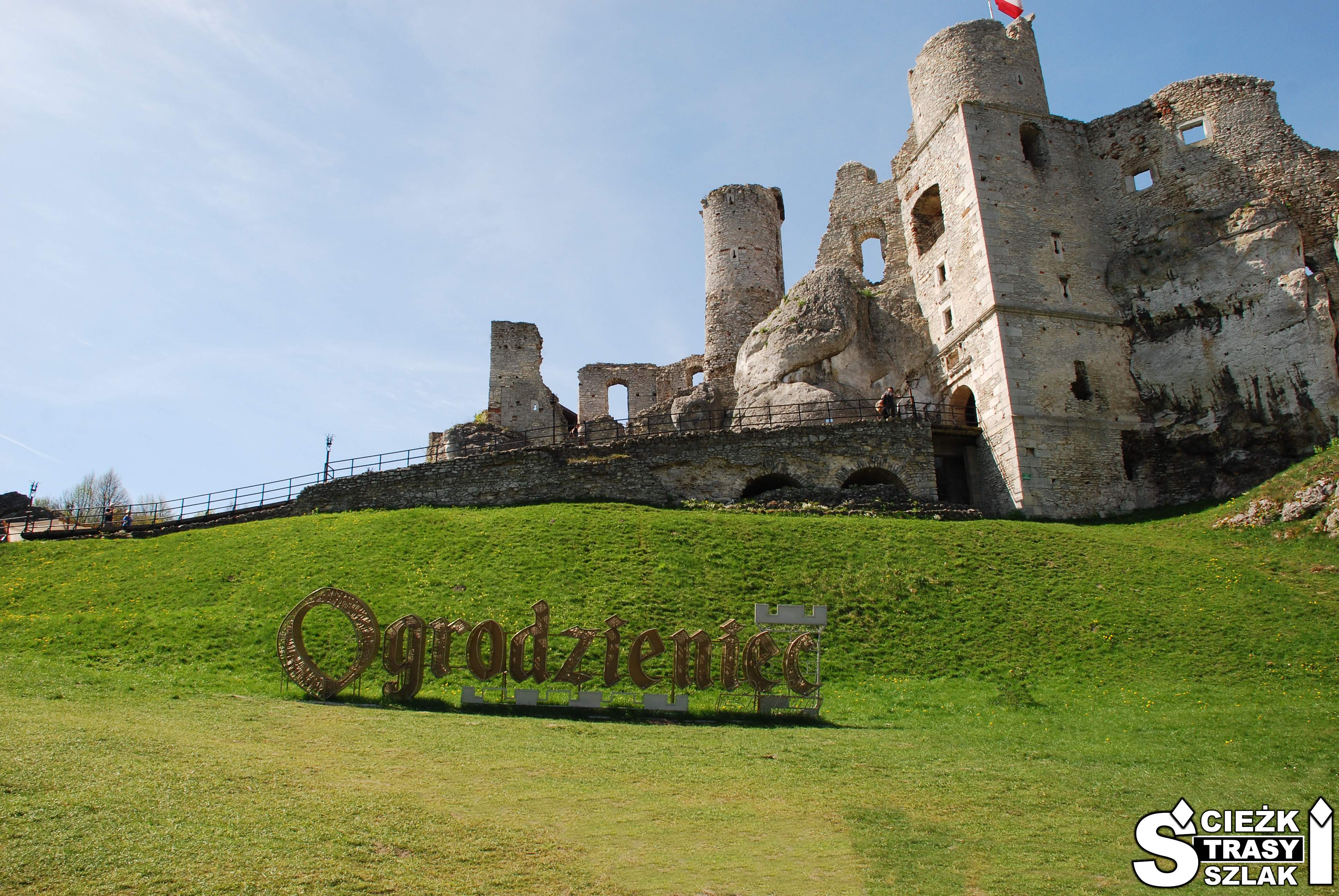 Duży, złoty napis z metalu “Ogrodzieniec” na wzgórzu gdzie wzniesiono Zamek w Podzamczu