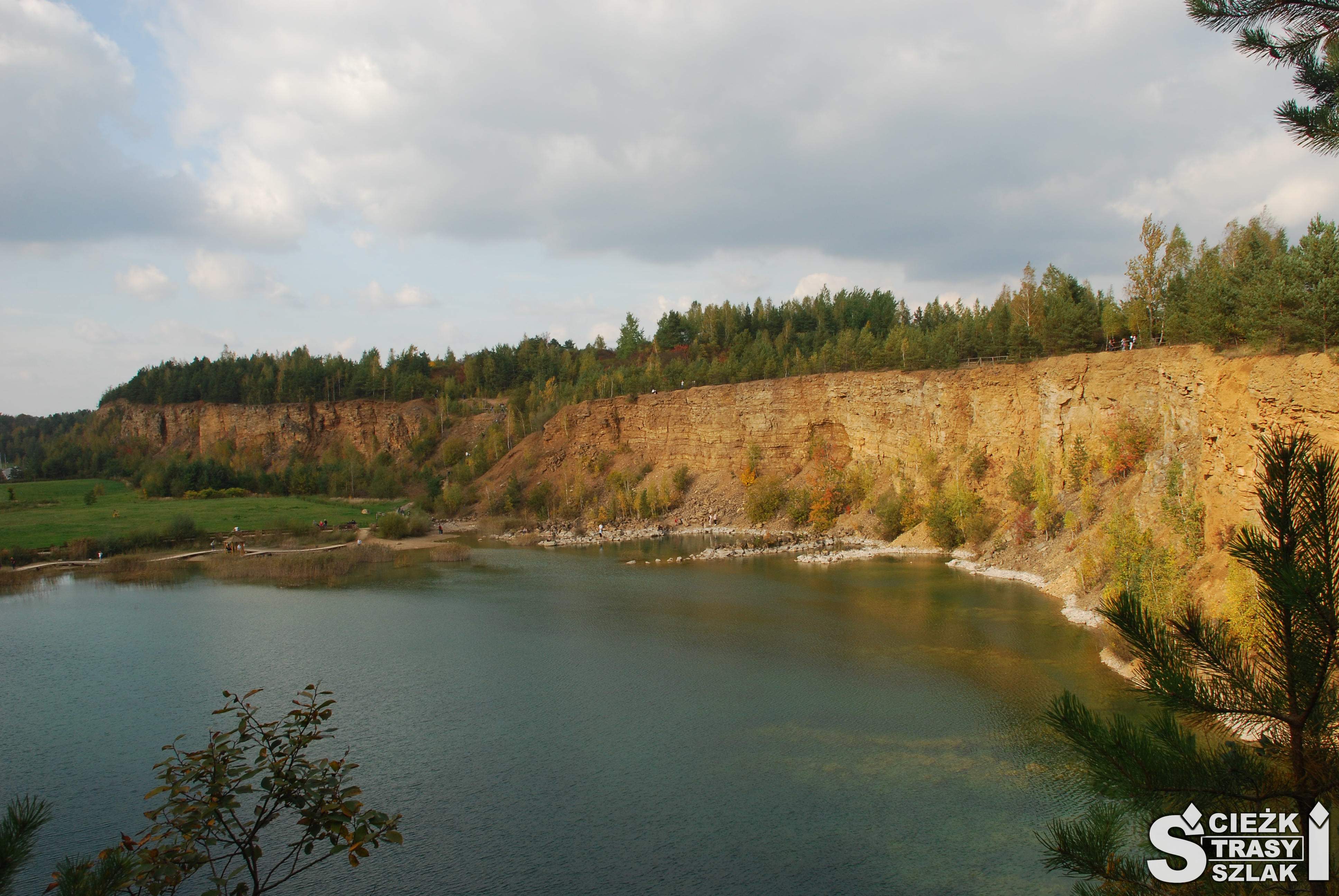 Turkusowe jezioro otoczone wysokimi skarpami kamieniołomu w Parku Gródek